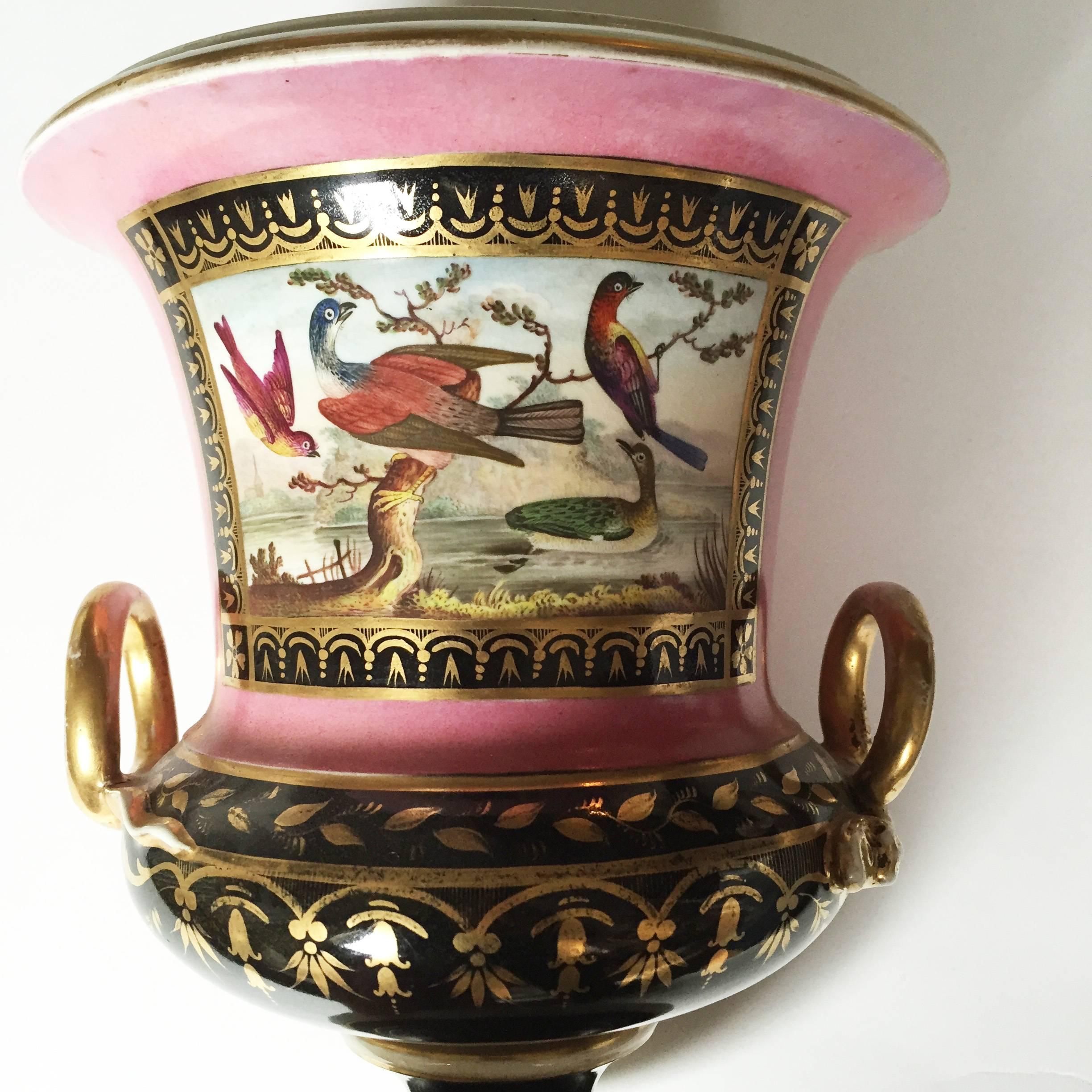 This Classic vase is painted with two ground colors, one rose pink and the other black, the campana (bell) shape body decorated with two applied looped handles molded with snake's head terminates. Both parts of the body are painted with bands of