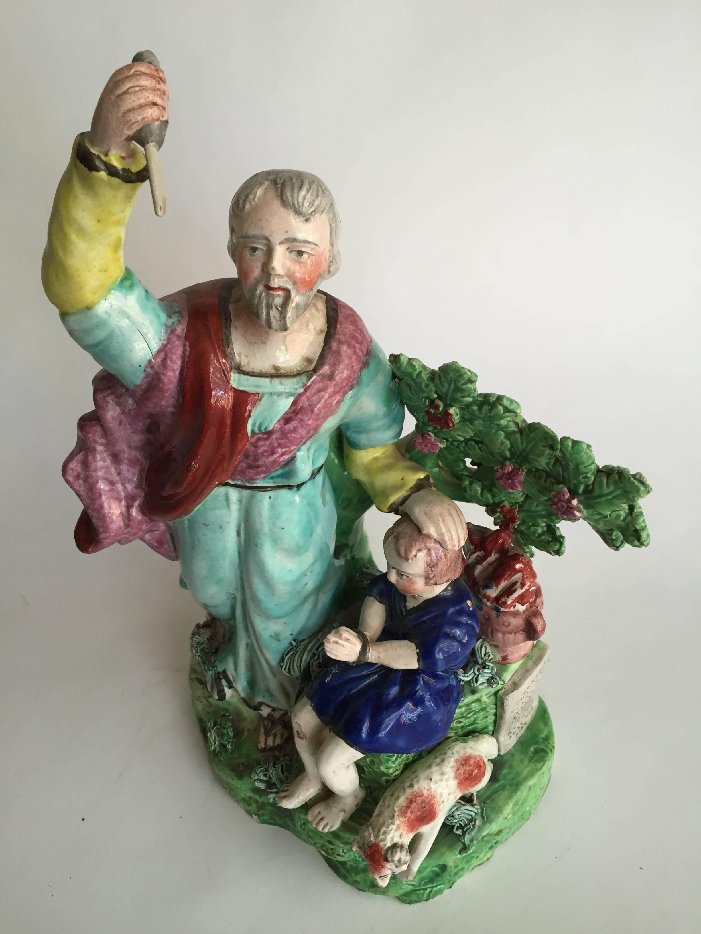 English Staffordshire Pottery rare figure of Abraham Offering to Slay Isaac. The somber figure of Abraham wielding a knife on the left side of the ovular, low-mounded green base, with the figure of Isaac seated under a tree issuing bocage to his
