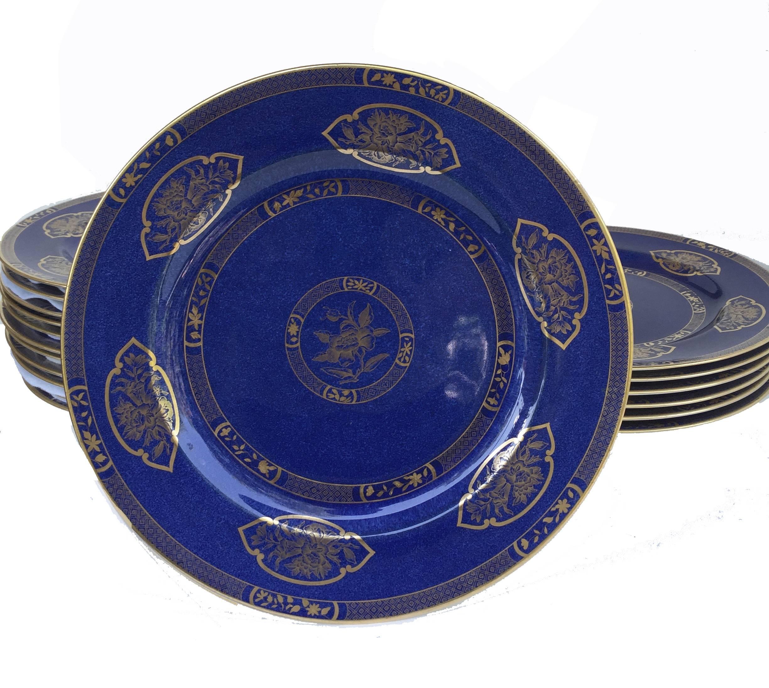 Wedgwood bone China set of 18 dinner plates, circa 1900, all of powder-blue ground, painted in gilt monochrome with chinoiserie pattern 8950, the rim and cavetto painted in gold with a band of cell-and-diaper border, alternating with stylized