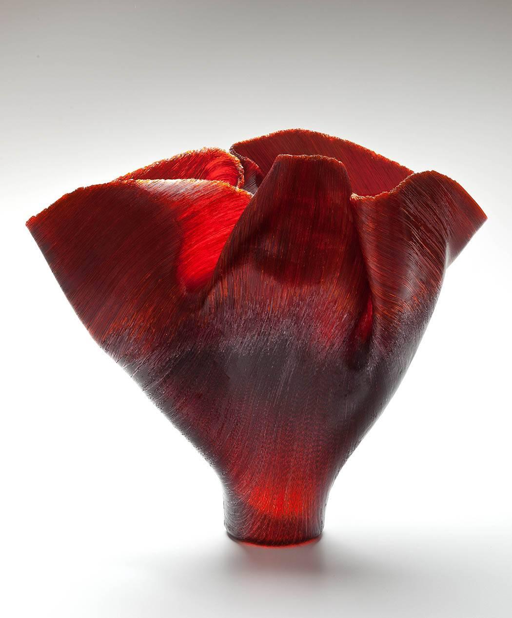 The vessel formed with hundreds of thousands of ombre red to warm black glass filament threads, fused uniquely within the kiln, and hand-pinched by Zynsky after the vessel is nearly complete. 

The works combines elements of material engineering,