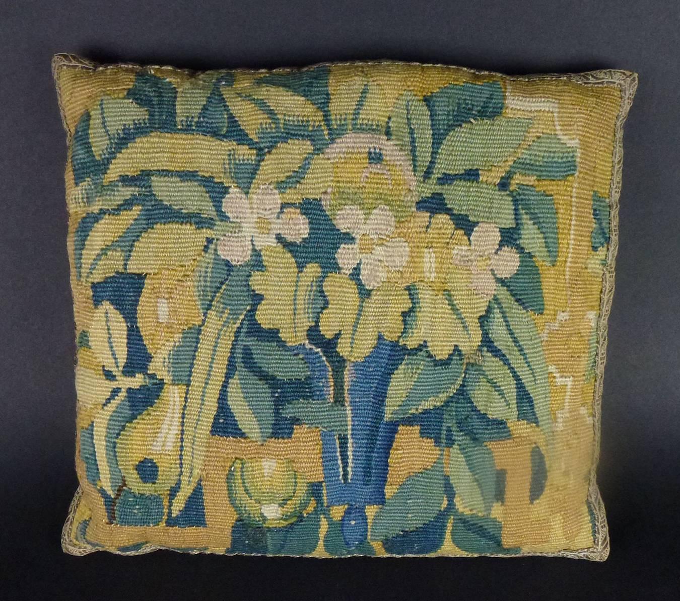 Three Baroque Brussels square tapestry wool and silk pillows, each woven with pastel-colored floral and stylized vase design on pale orange field, the needlework woven in wools and silks in naturalistic hues, each edged with antique silver-thread