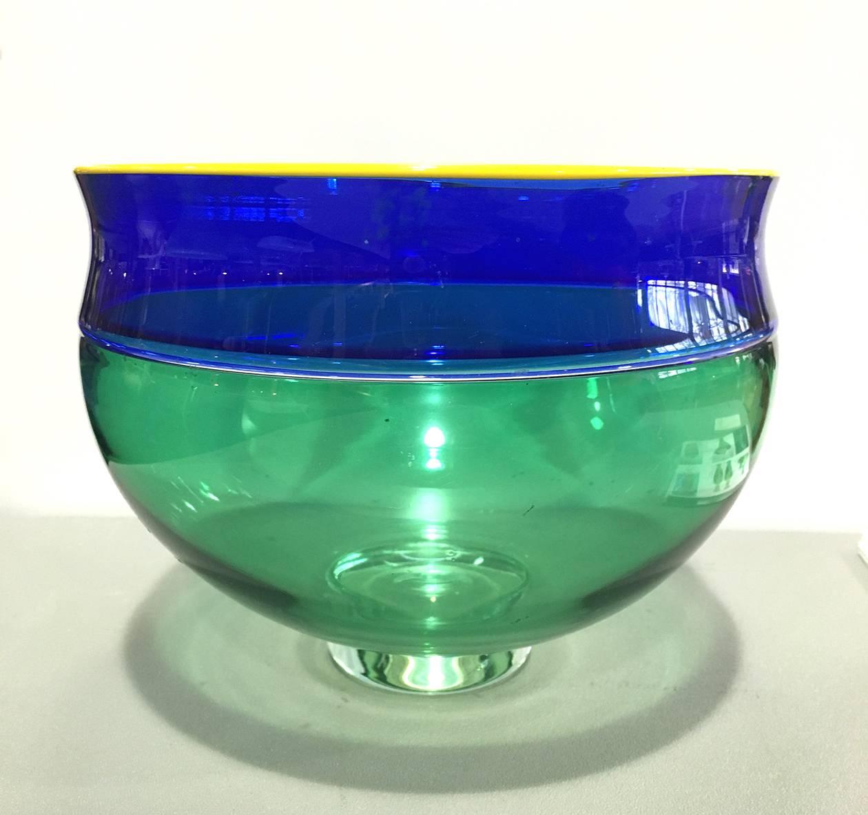 American Alex Brand (B. 1950s) glass Incalmo bowl blue green yellow, 1999

The wide mouth with narrow yellow lip wrap over a waisted blue band, over a pale green bowl, on a cased pale green glass foot. 

Signed, Alex Brand to underside.