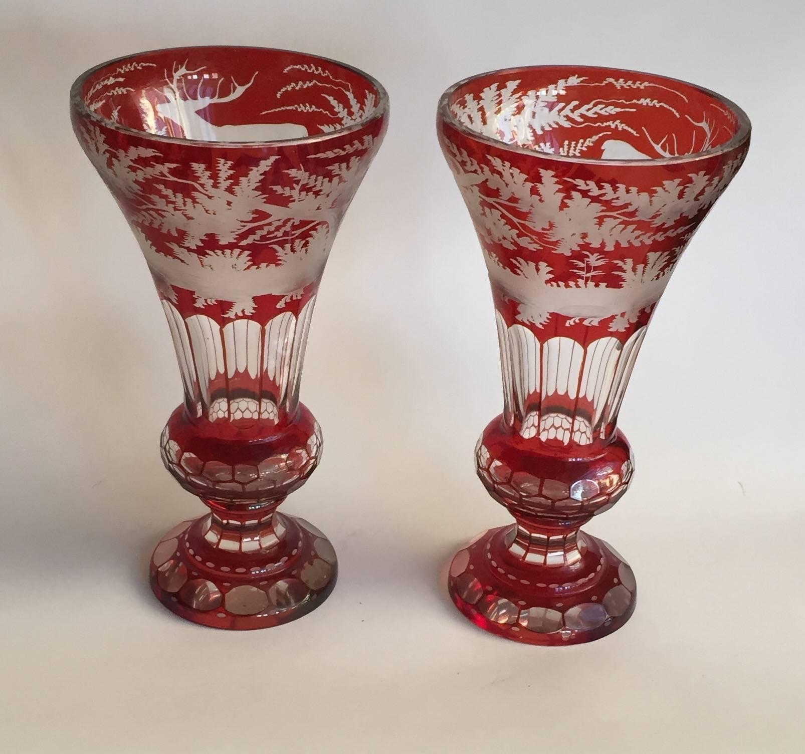 Pair of bohemian part ruby-stained vases, the trumpet-form bodies with upper panels stained in ruby and engraved with stags in continuous woodland landscapes, the clear ground panels with red lines delineating each section, the ruby-stained bulbous