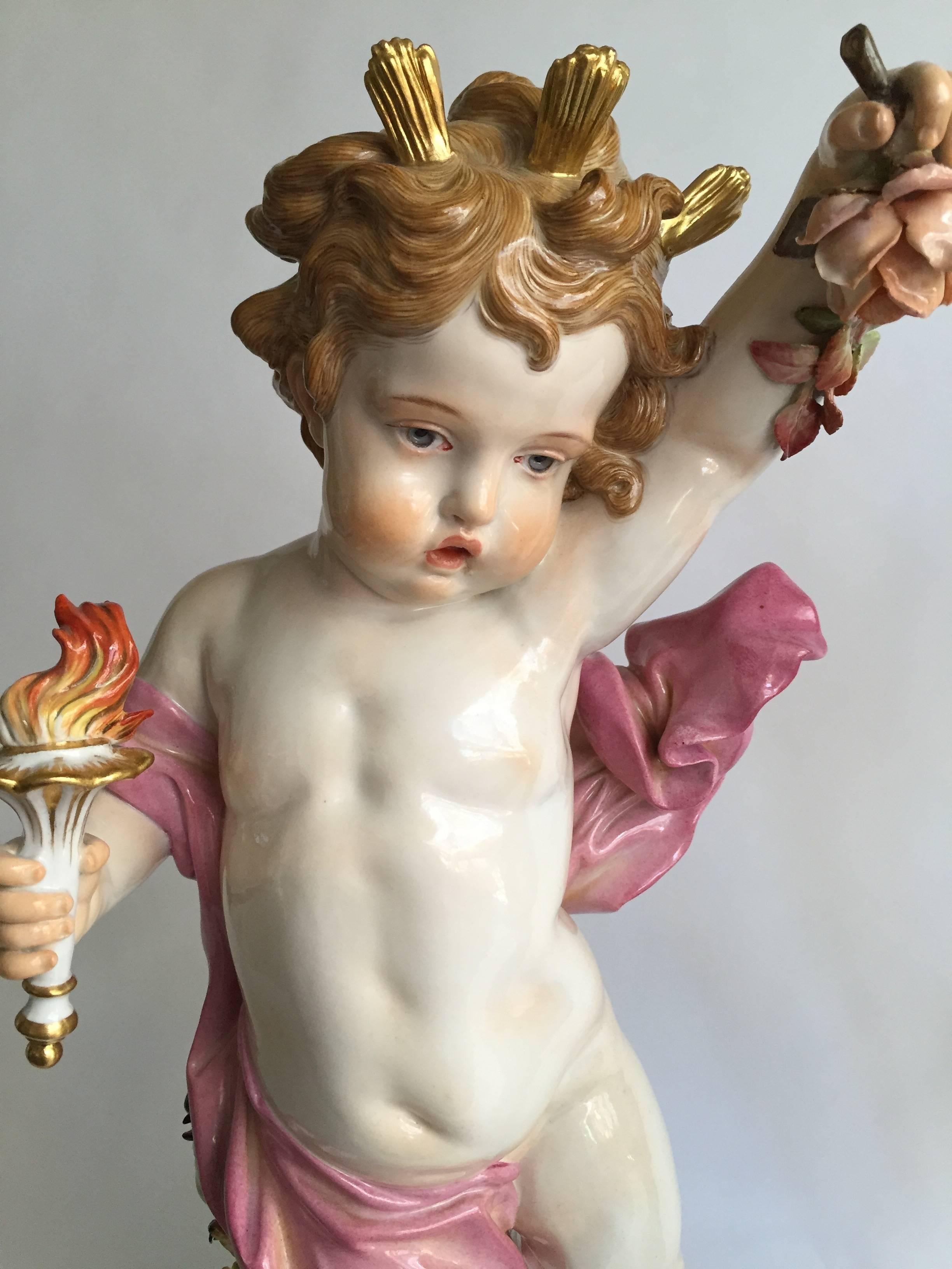 German Meissen Porcelain, pair of figures of putti emblematic of night and day, modeled by Heinrich Schwabe, 1877-1880, each standing atop a gilt dome the figure of day holding aloft a flaming torch, with a sunflower and bird to her side, clad