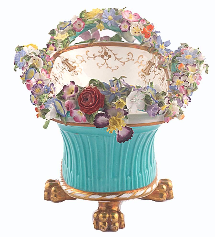 English Coalbrookdale Porcelain quadrapodal basket, with four handles extensively encrusted with flowers, the interior well finely painted with a scene of figures in an extensive landscape, under a gilt-line and scrolling foliate border. The