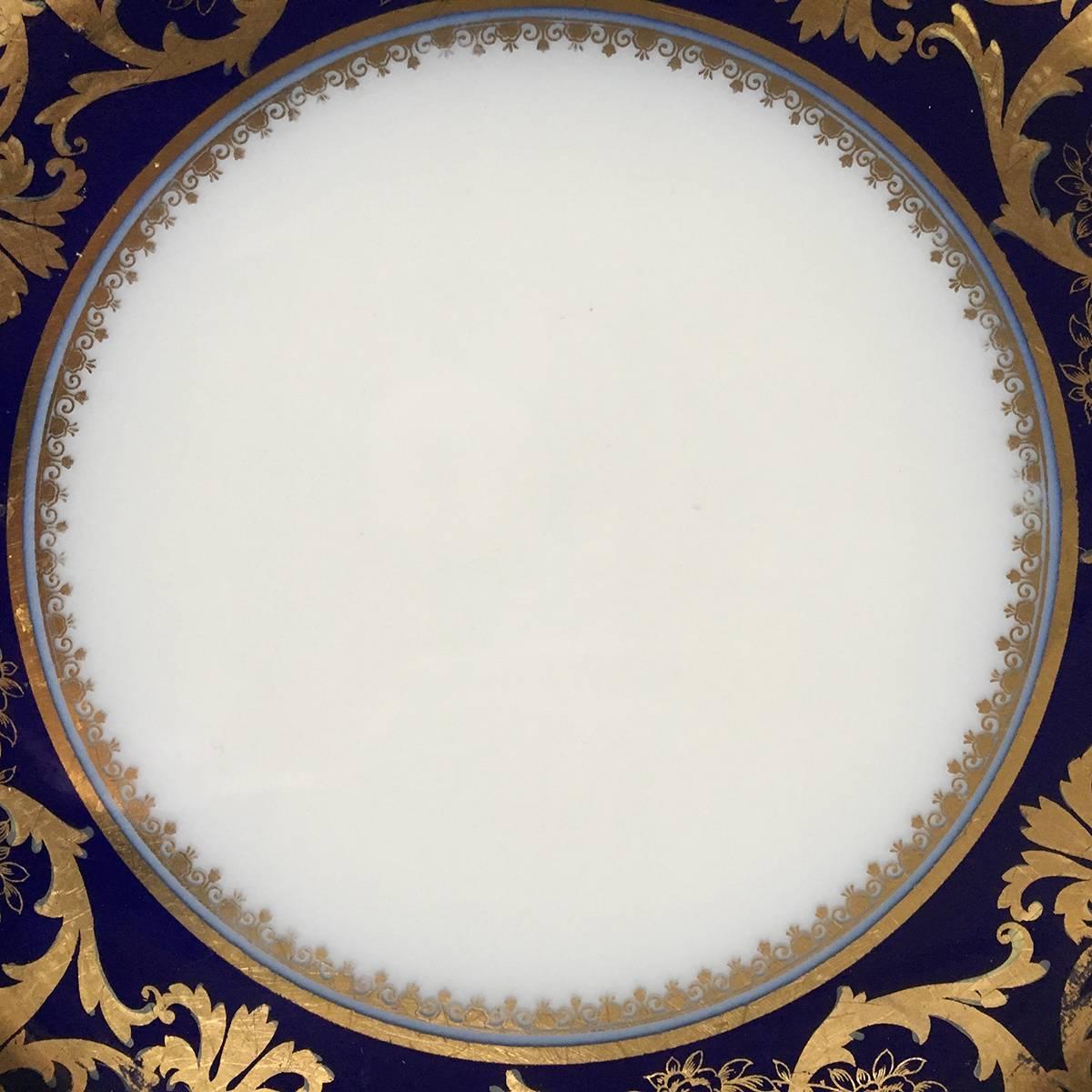 Bernardaud & Co., Limoges France set of four porcelain dinner plates molded with wide shoulders, the very dark blue band to rim encrusted with raised paste gilding in two colors.

 Marked B & Co. , Bernardaud & Co. Limoges, twice, in green and in