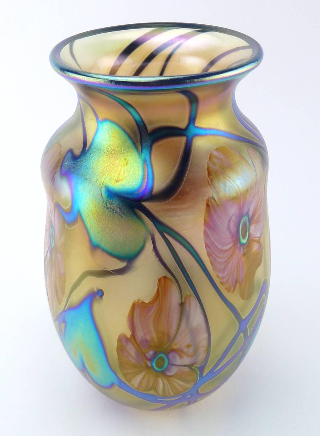 Charles Lotton (B. 1935) Studio art glass vase multi flora gold iridescent design, 2002, the everted mouth over the waisted neck, the cylindrical body with ovate base, with pink flowerheads on green-blue iridescent vines.

Signed Charles Lotton.