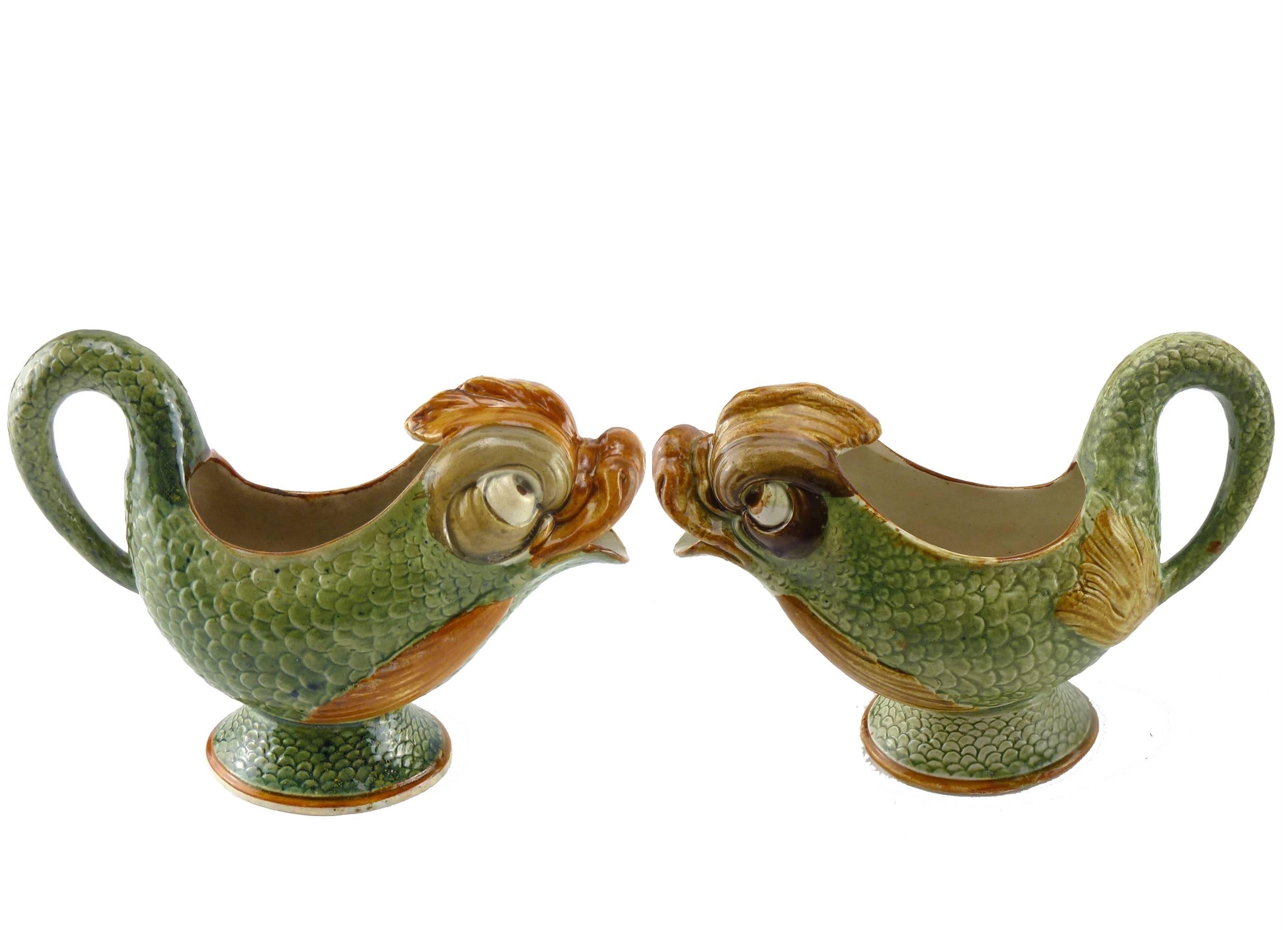 Matched Pair of English Pearlware Dolphin Cream Jugs Circa 1800, each modelled with green enameled fish scales to the sides, the lip modelled as the dolphin's open mouth and painted with ochre enamel, the handle modelled as the dolphin's