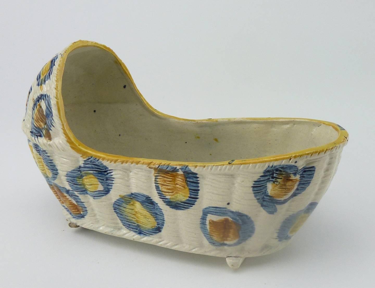 English Staffordshire Pearlware Prattware model of a cradle or moses basket

the ovate body with upper section, modelled to resemble woven rushes with vertical staves, with a rope-twist edge and border between upper and lower head area. Cradle