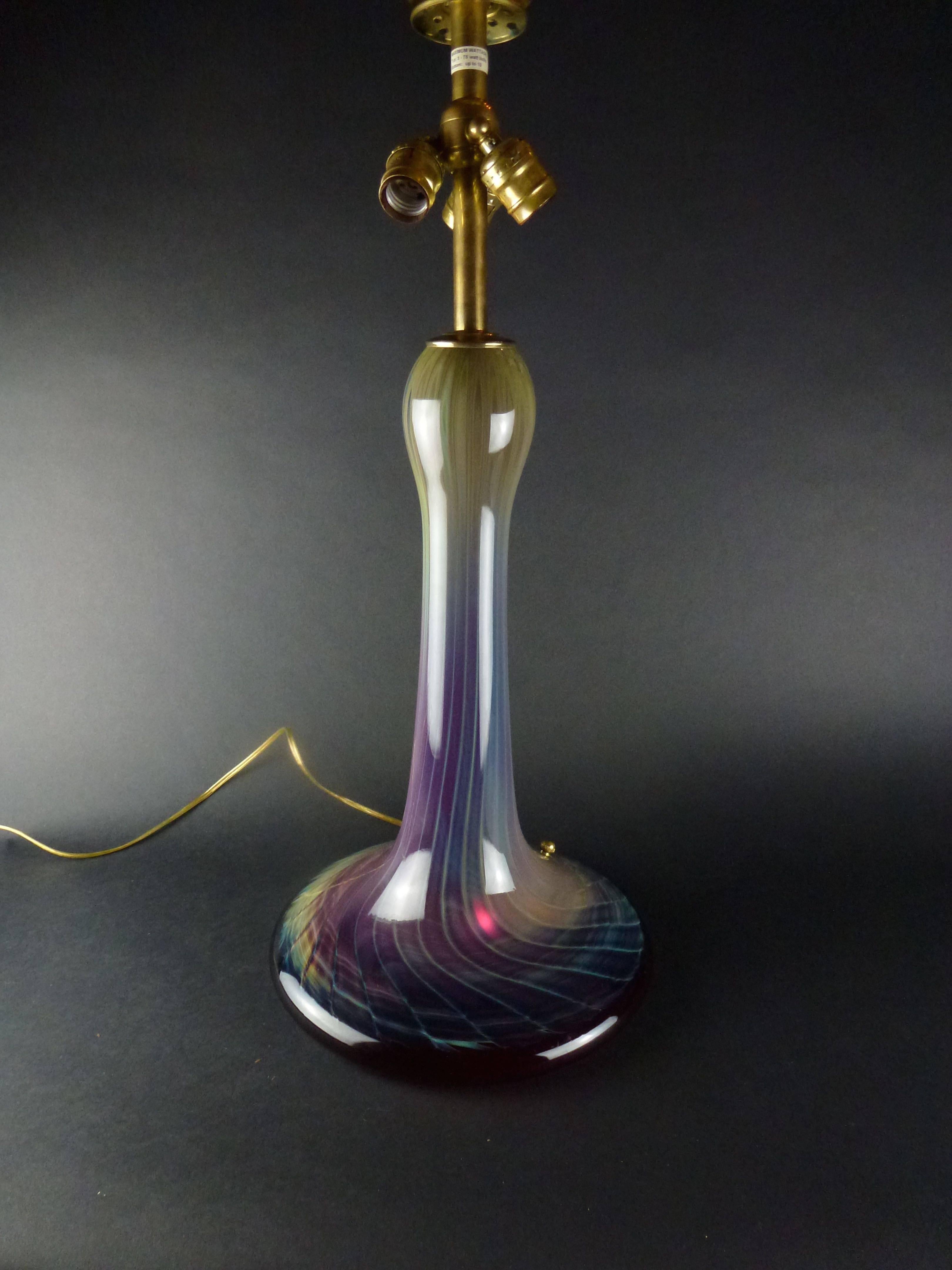Joe Clearman studio glass blown glass table lamp with blue, purple and red streaks. There are bulbs in the shade and a bulb in the stand. 

Signed Joe Clearman to the base.

Size: 28
