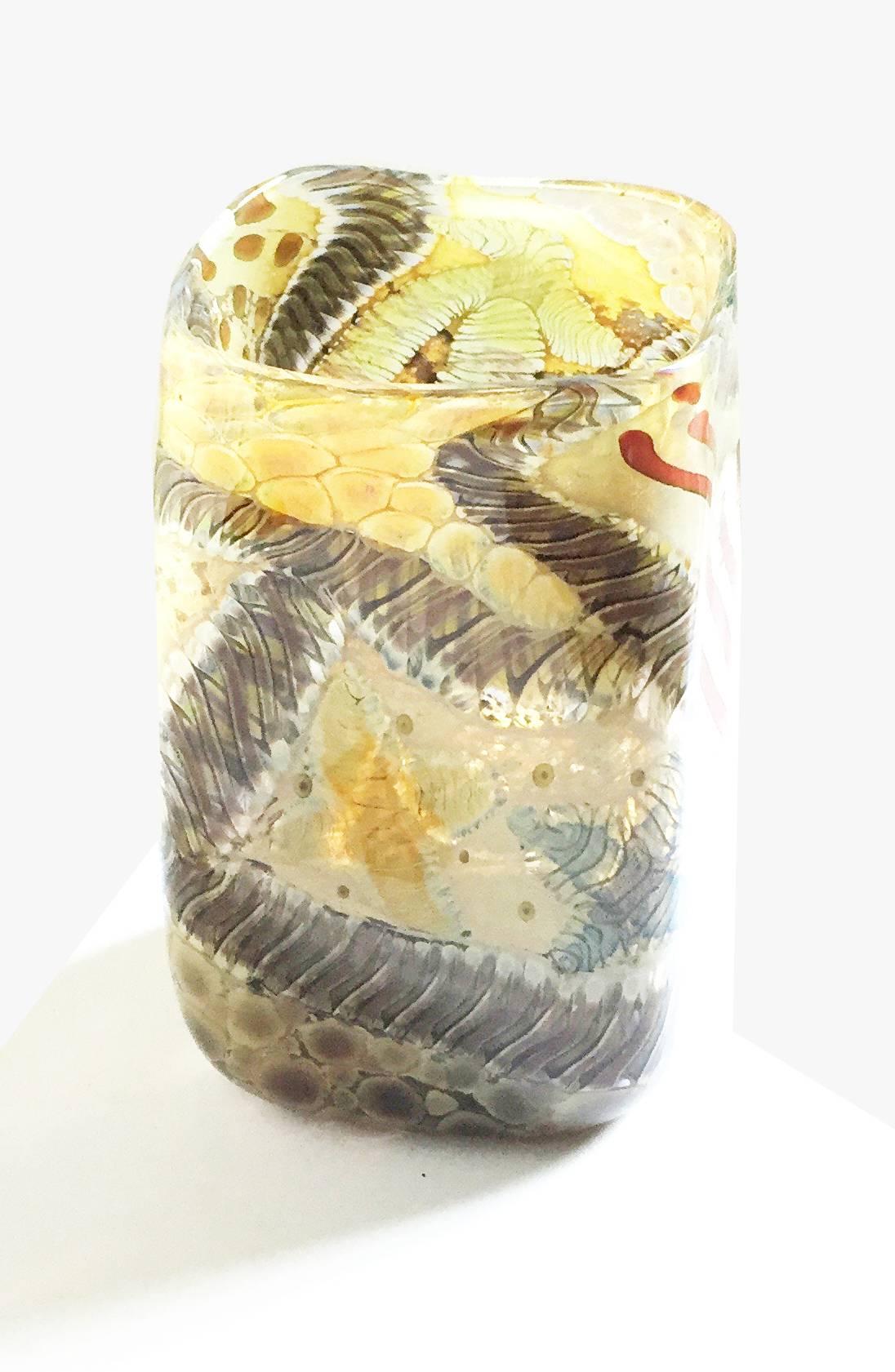 Contemporary Studio Glass vase by Kenny Walton the rectangular vase enamelled with white, red, green, yellow, ochre and blue elements that wind around like troglodytes and other ancient life forms.

American glassblower Kenny Walton (? - 2010) was