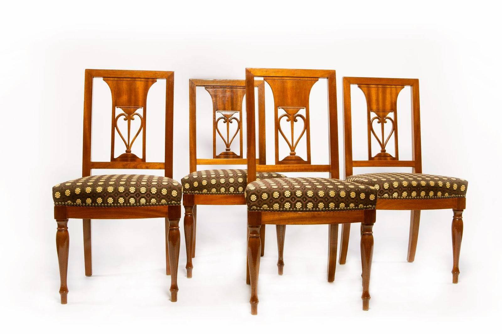 A fine set of 14 Empire mahogany dining chairs, a pair of arms and 12 sides, upholster in a brown French horse hair fabric with a gold colored medallions with a nailhead trim. The chairs having a center design to the back with a simple seat real