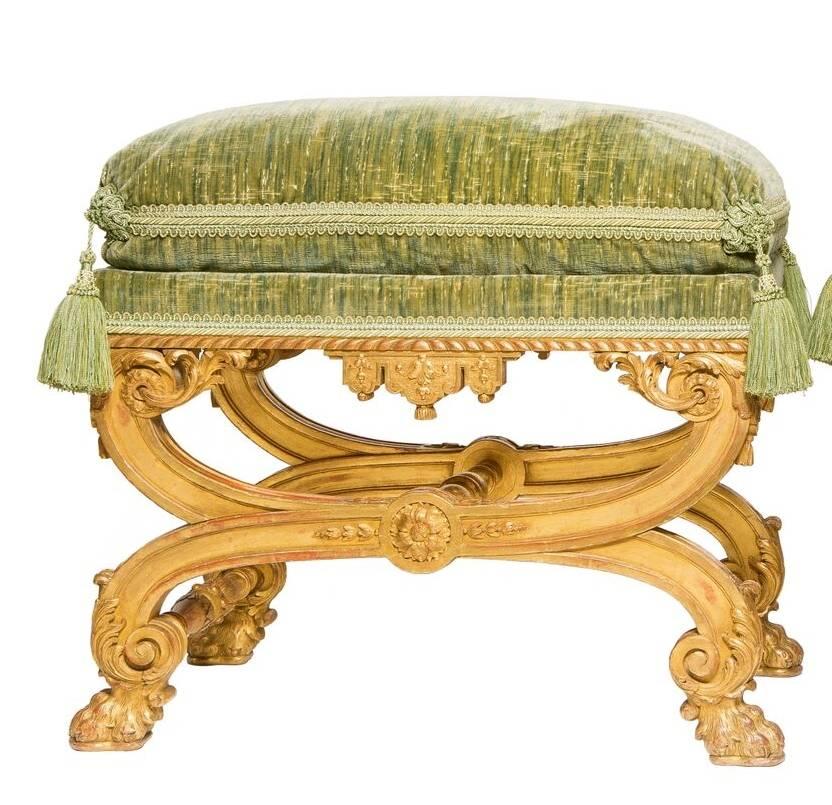 A very fine pair of Regence style giltwood Tabourets, these finely carved stools with a gadrooned apron with tassels and foliate and medallions, sunflower medallions to the center to the palette-headed foliate scrolled above lion-paw feet.