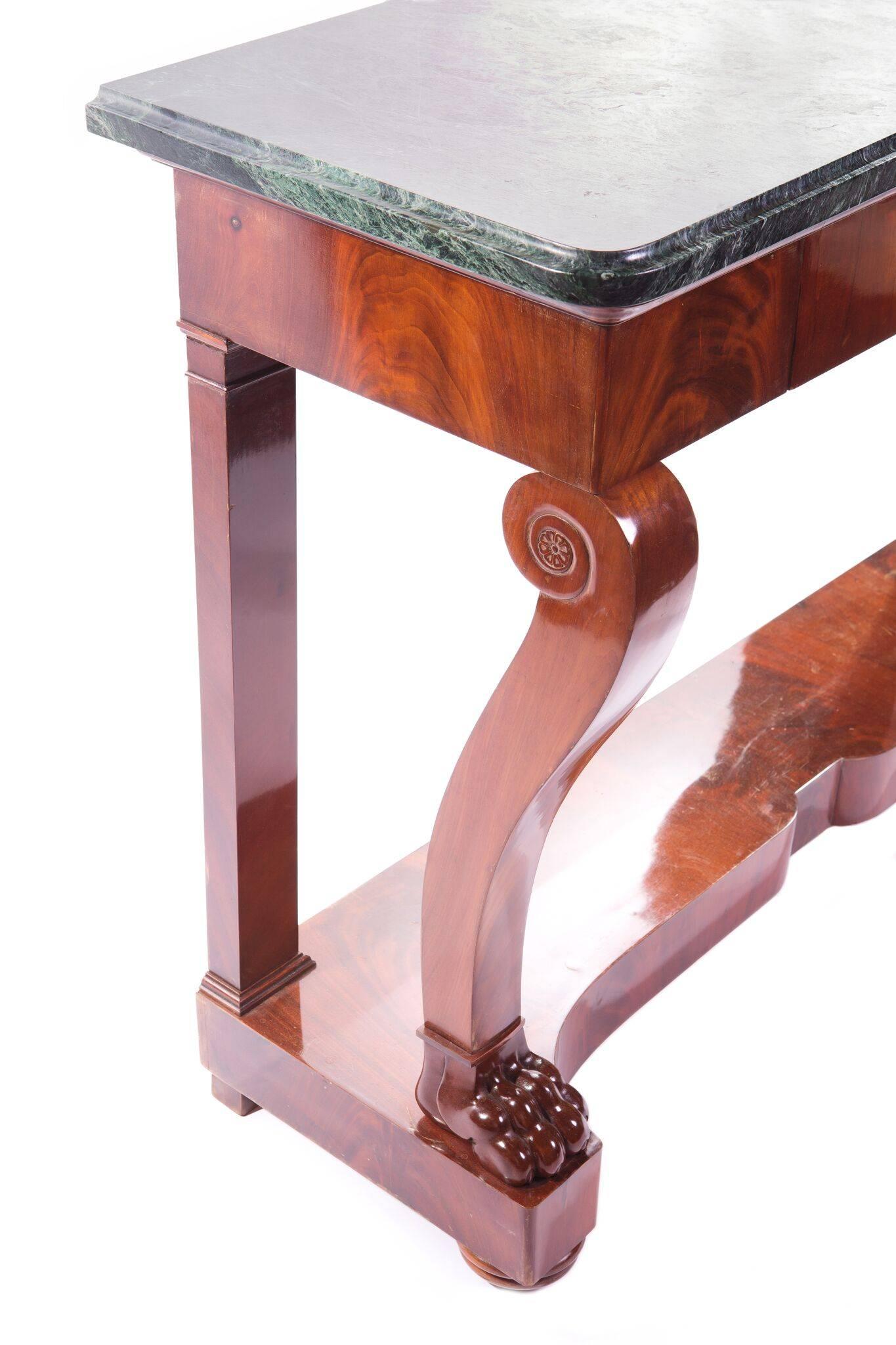 A Empire mahogany console with a center drawer apron resting on carved front legs ending on paw feet and two back legs on a shaped base with a green marble top. 
The back of the console is stamped with a château stamp.
