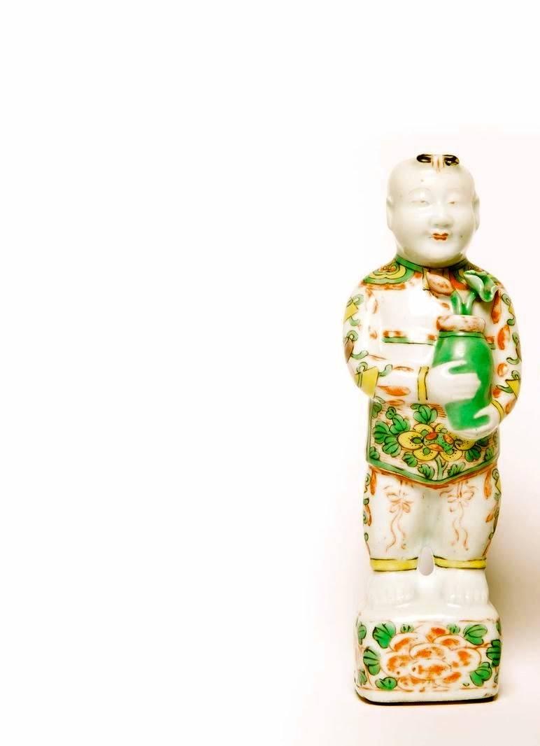 A pair of Chinese Famille Verte porcelain Hoho figures of boys holding pots with Lotus flowers on bases, decorated in the Famille rose style.