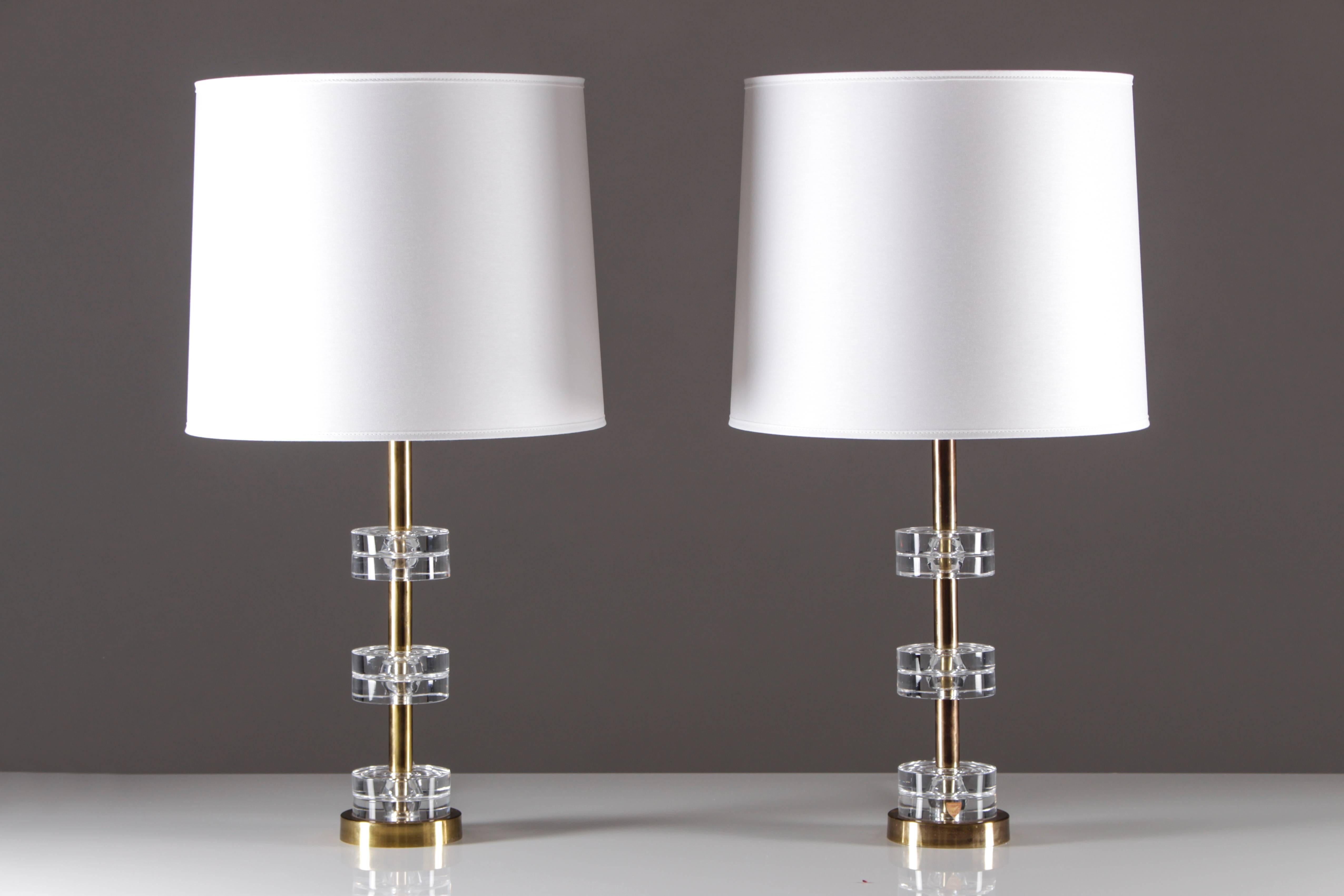 A beautiful pair of Swedish table lamps in brass with glass discs by Carl Fagerlund for Orrefors. The lamps feature six glass discs separated by brass rods. The lamps are in excellent condition with some patina on the brass details. The lamps are