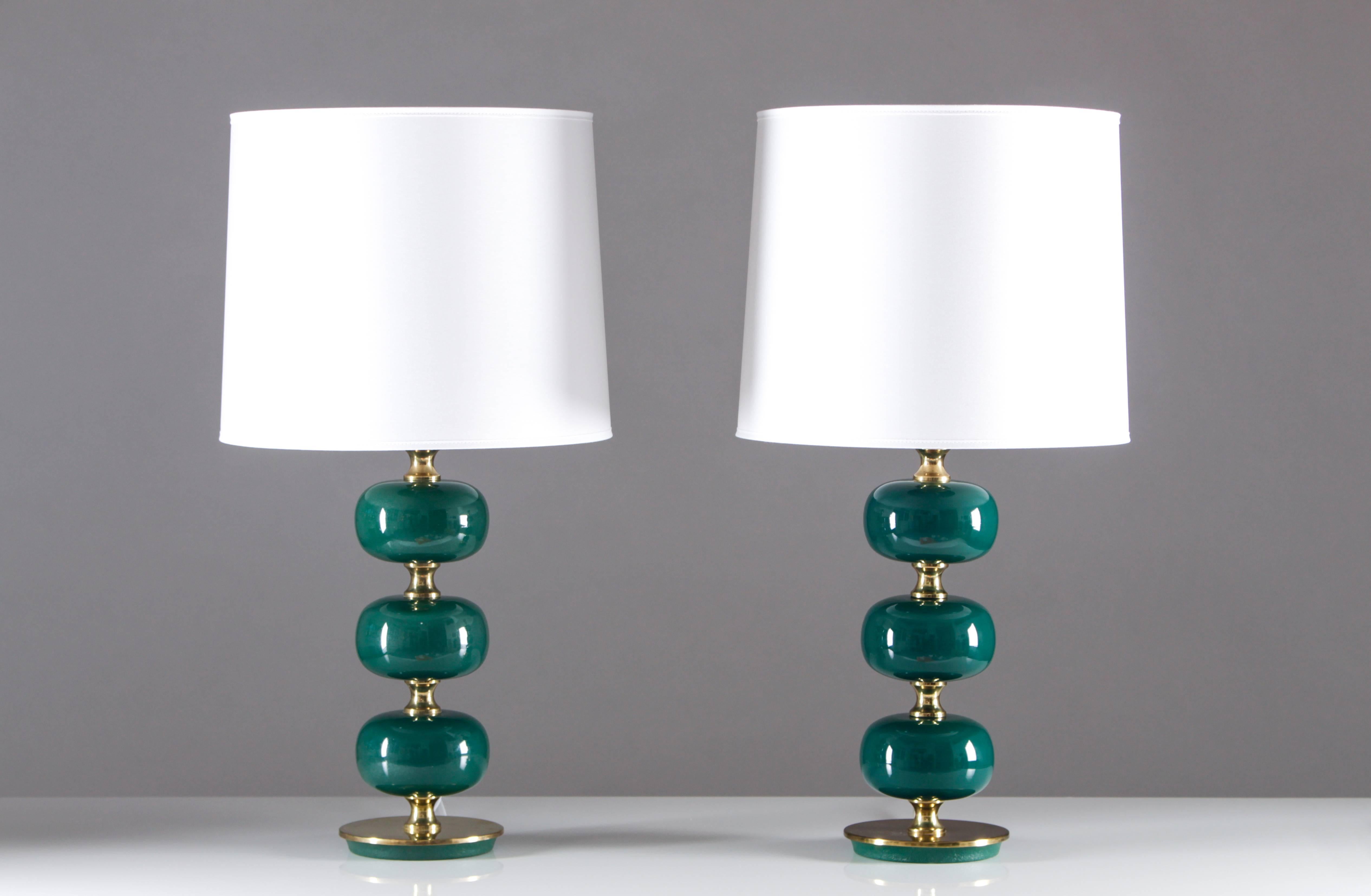 This set of two Mid-Century table lamps was manufactured between the 1960s and 1970s by Stilarmatur Tranås in Sweden. The lamps feature three green glass spheres with brass feet and details. The lamps have been rewired. The lamps are in good vintage