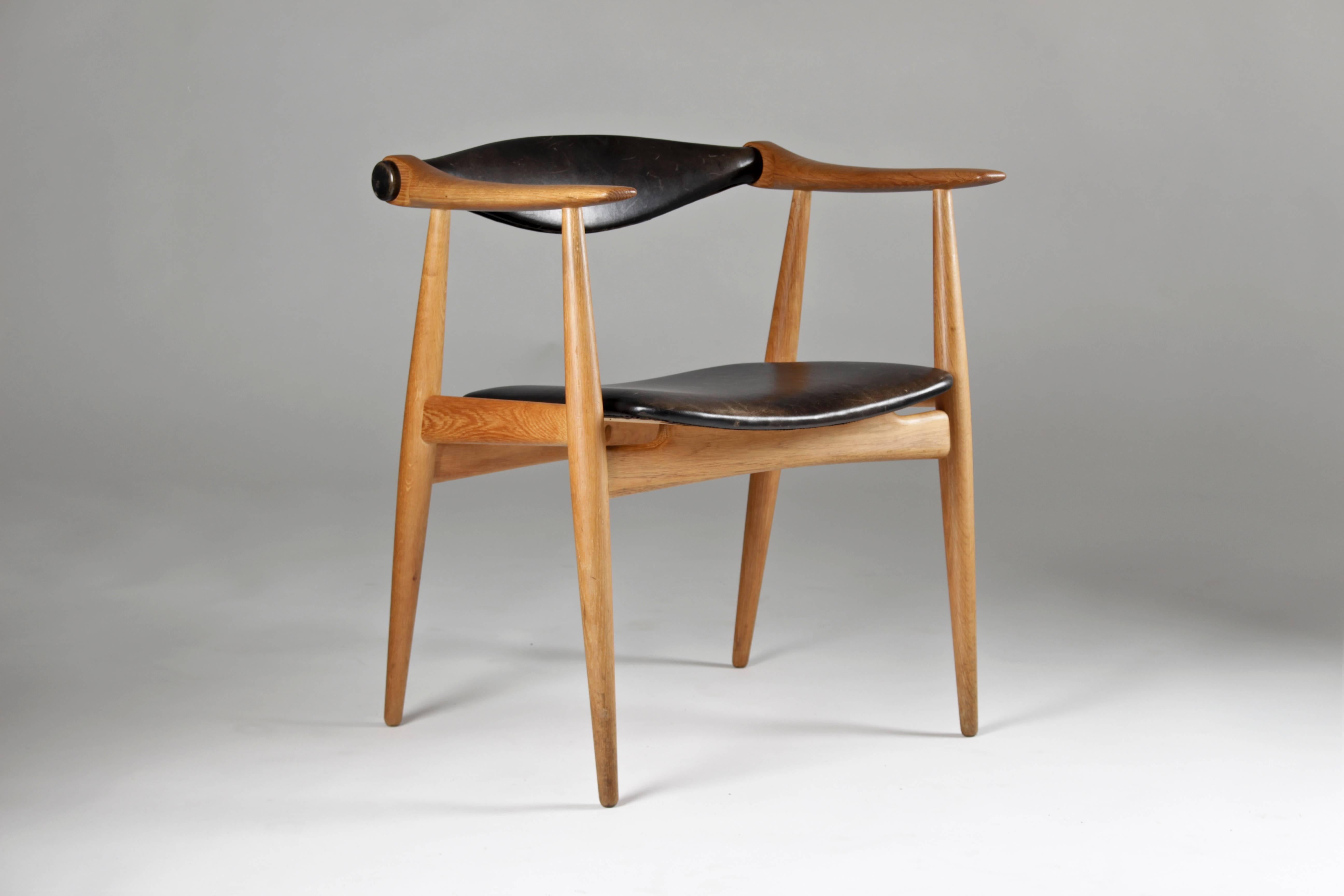 Hans Wegner CH-34 in with oak frame and black leather seat. This chair was in production between 1959 and 1964. It is in a perfect original condition, showing a soft patina on the leather parts. The 360 degrees rotating back rest makes this chair