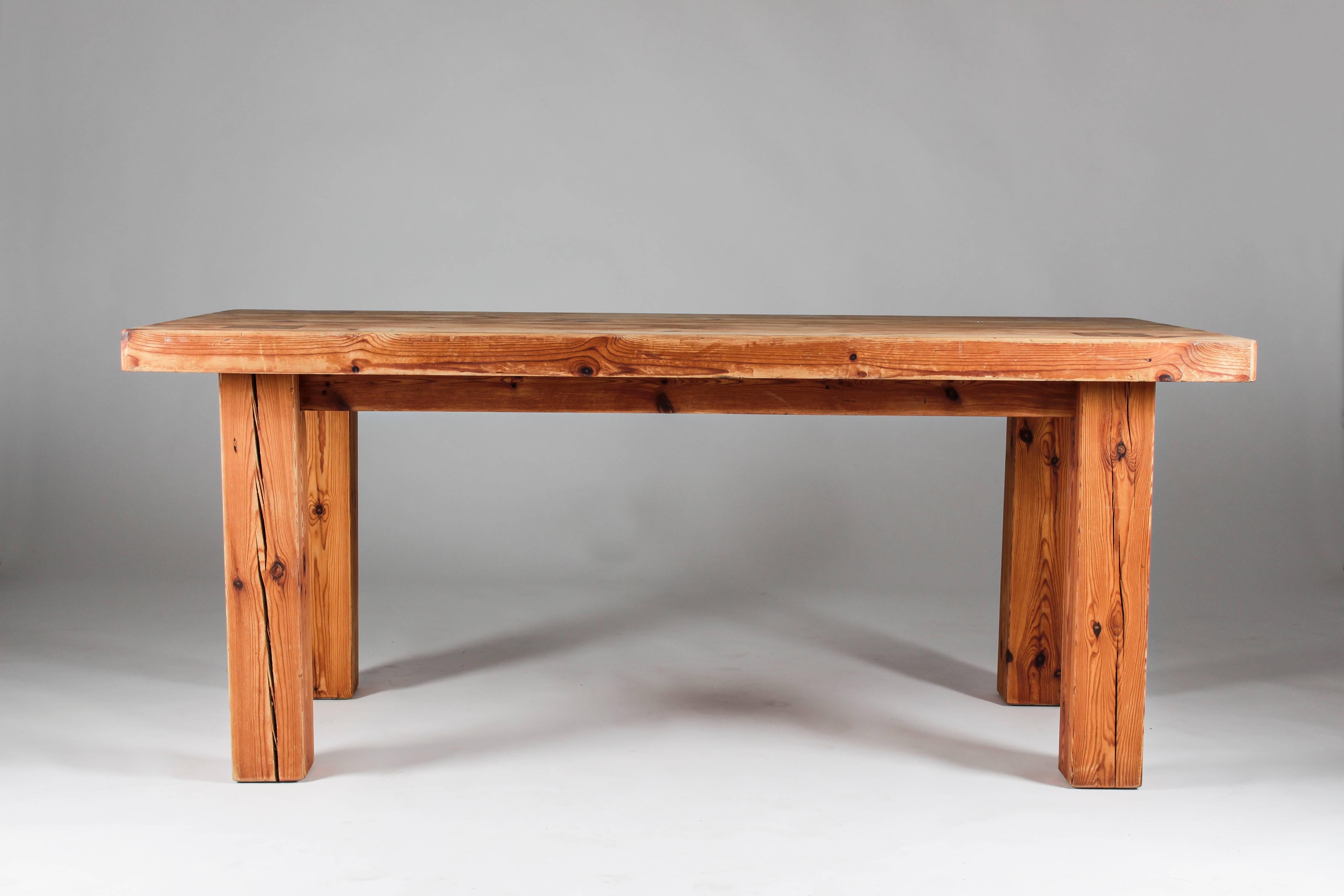 Very heavy table in pine, brutal and elegant at the same time, with its legs beautifully coming through the table top. This is probably a one of a kind table. The text under the table top says 