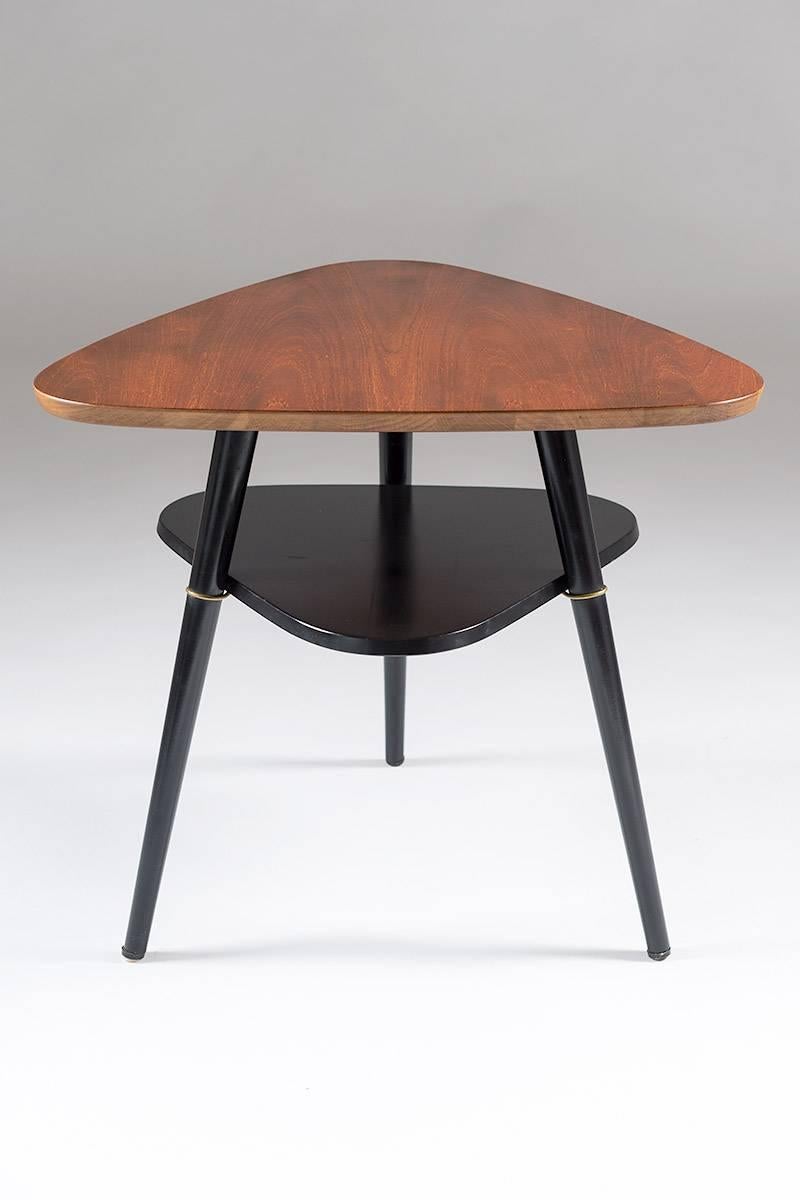 A beautifully shaped side table designed by Nils Jonsson for Hugo Troeds in Sweden. The triangle-shaped tabletop is made of teak and the rest of the table is black lacquered with details in brass. 
This table is in an excellent vintage condition.
