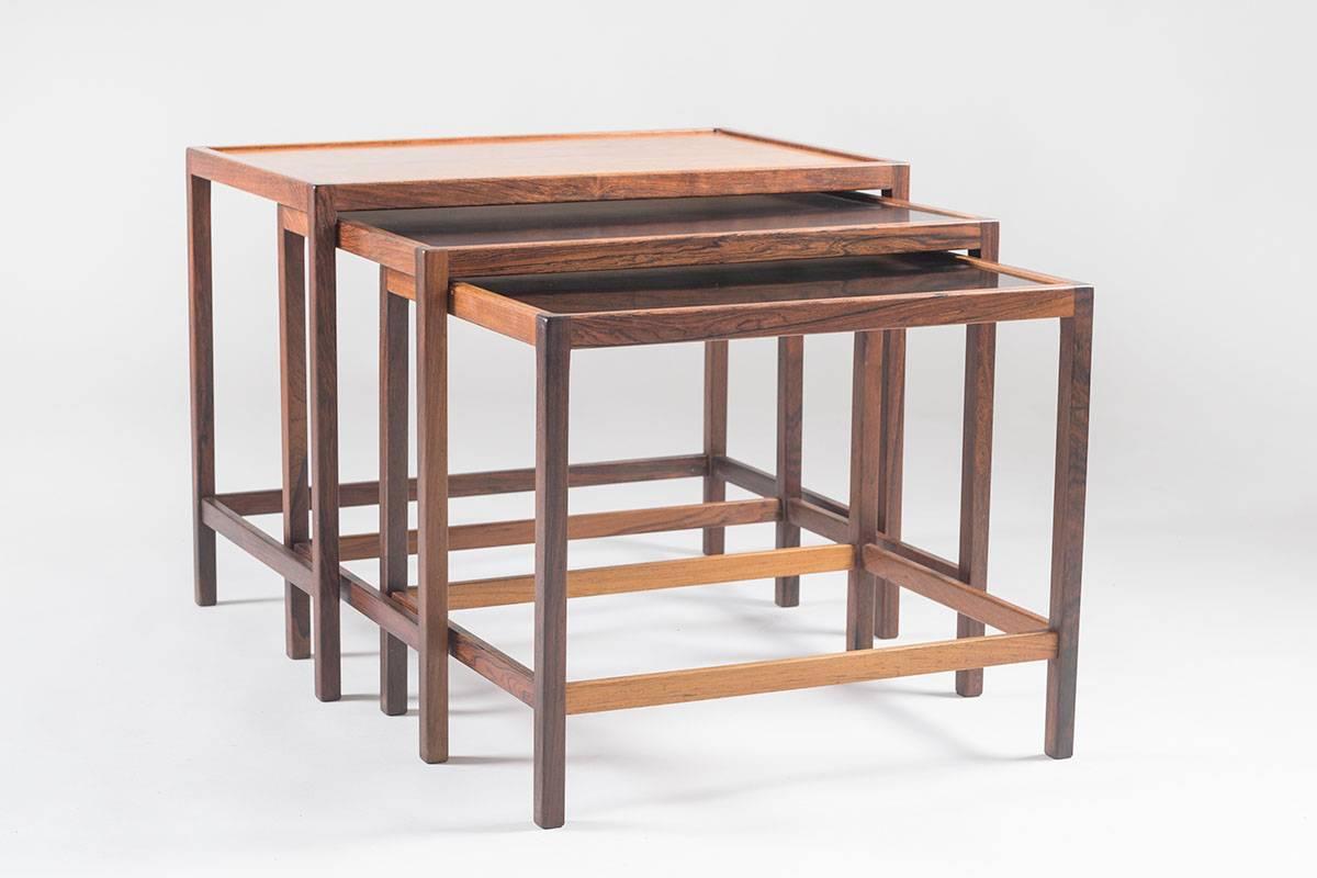 Set of three nesting tables. One table with rosewood top and two smaller tables with formica top, sliding under each other. These tables were designed by Kurt Østervig for Jason Møbelfabrik, Denmark. The tables show great quality in every detail,