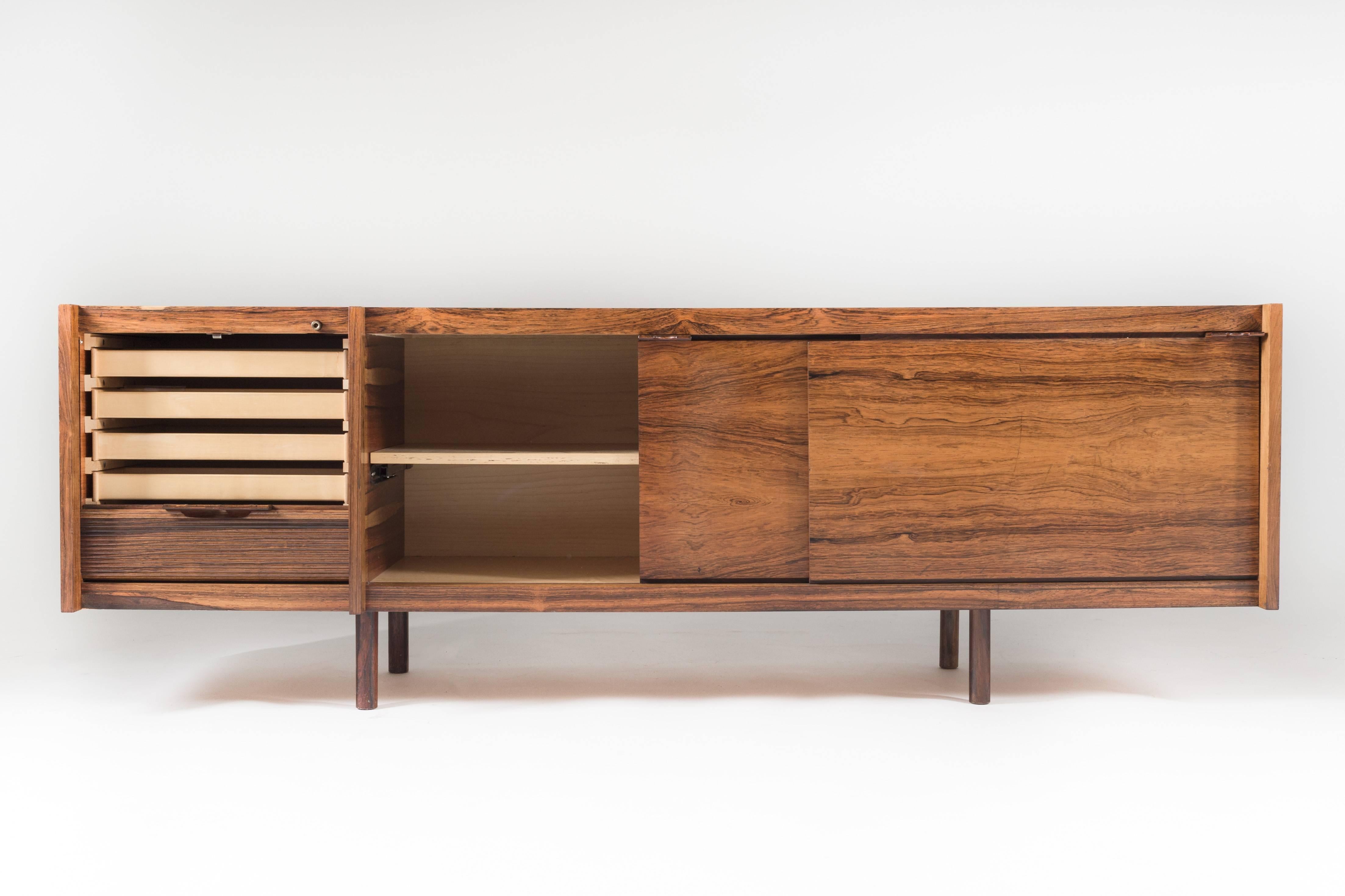 Rare sideboard in rosewood by Norwegian designer Sven Ivar Dysthe for Dokka Møbler. The sideboard features two sliding doors and a tambour door hiding multiple drawers. The beautiful grain in the rosewood together with the elegant handles on the