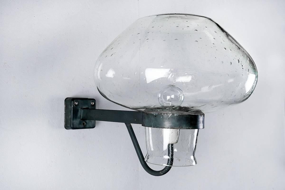 Applique d'extérieur par Gunnar Asplund pour ASEA, années 1940. Cette lampe présente un très grand abat-jour en verre transparent, reposant sur une structure en métal peint. Les bulles dans le verre donnent un beau motif de nuances dans la lumière.