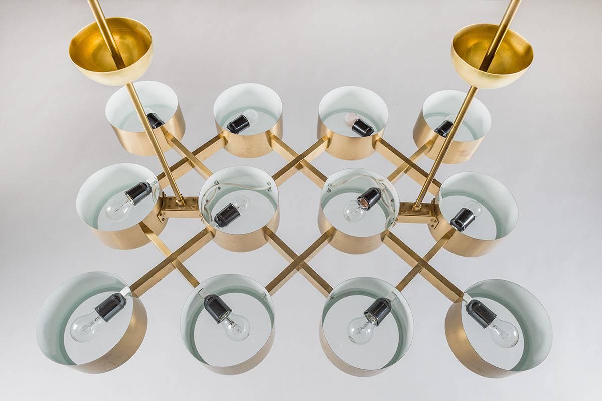 A set of two chandeliers by Hans-Agne Jakobsson, Sweden.
This model is very rare and among the finest that Hans-Agne designed.
They feature twelve-light sources per lamp. Each bulb is surrounded by a circular brushed brass cylinder with a frosted