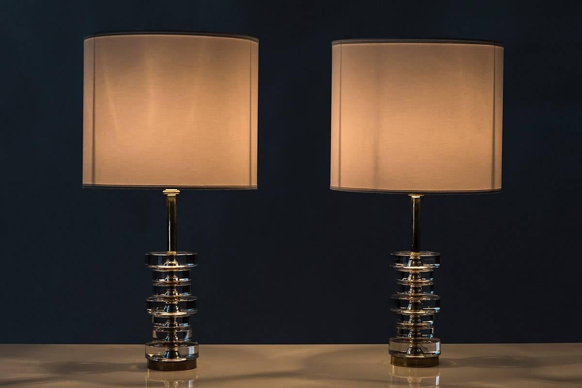 A pair of magnificent table lamps by Carl Fagerlund for Orrefors, Sweden.
The lamps consist of seven discs made of clear crystal glass, resting on a base of brass.
Condition: The lamps are in excellent condition and have been rewired. 
Please not