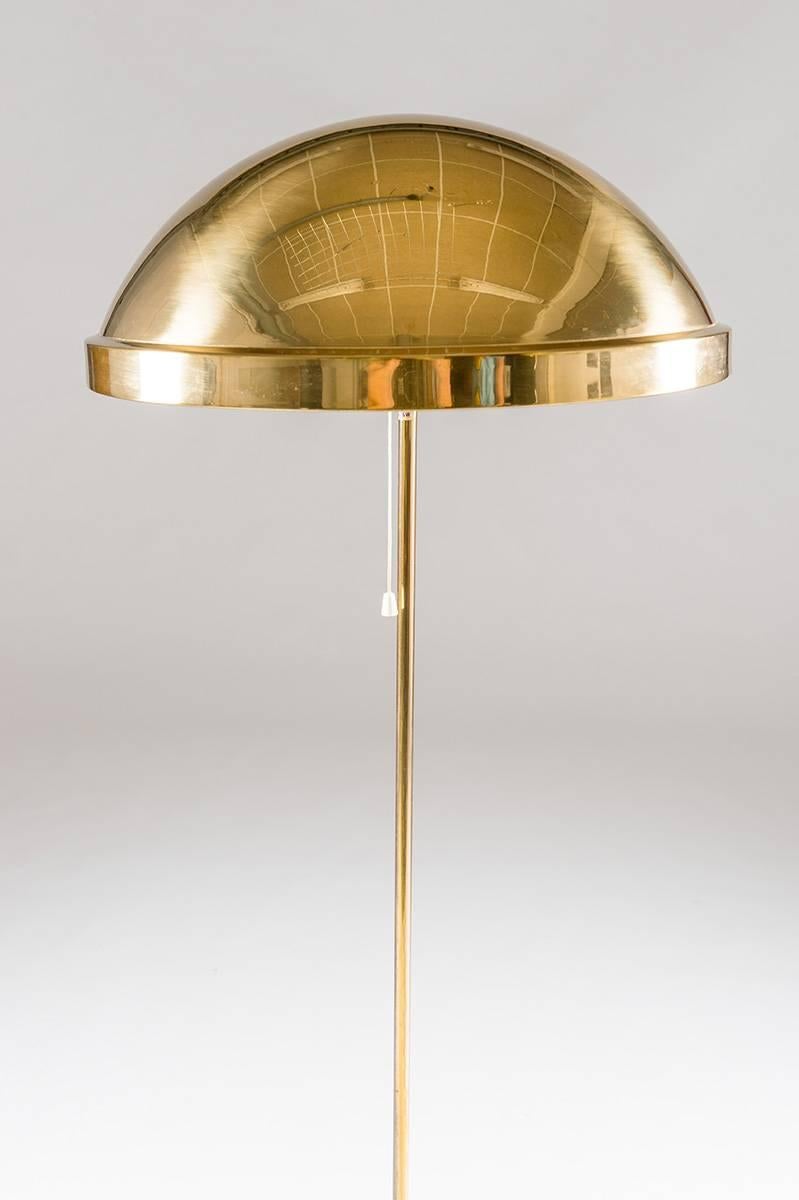 Floorlamp in solid brass by Eje Ahlgren for Bergboms. This rare model was only in production for a short period of time. It features a thin brass pole, holding a large solid brass shade that rests on three metal strings. 
Condition: Some light