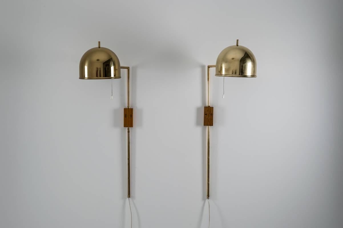 Set of four wall lamps in brass, model V-75 designed by Eje Ahlgren for Bergboms. 
The rod is held by a wooden block and the height can be adjusted.

Condition: Very good vintage condition, minimal dents on two of the shades (impossible to catch
