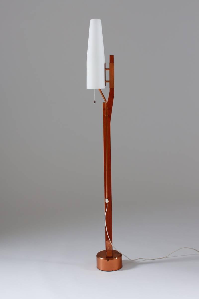 Stunning floor lamp from Orrefors with original opaline glass shade. This lamp is extremely rare, and was probably made in a very limited quantity by Swedish glass factory Orrefors. The lamp has beautiful details in copper, a base in teak and shade