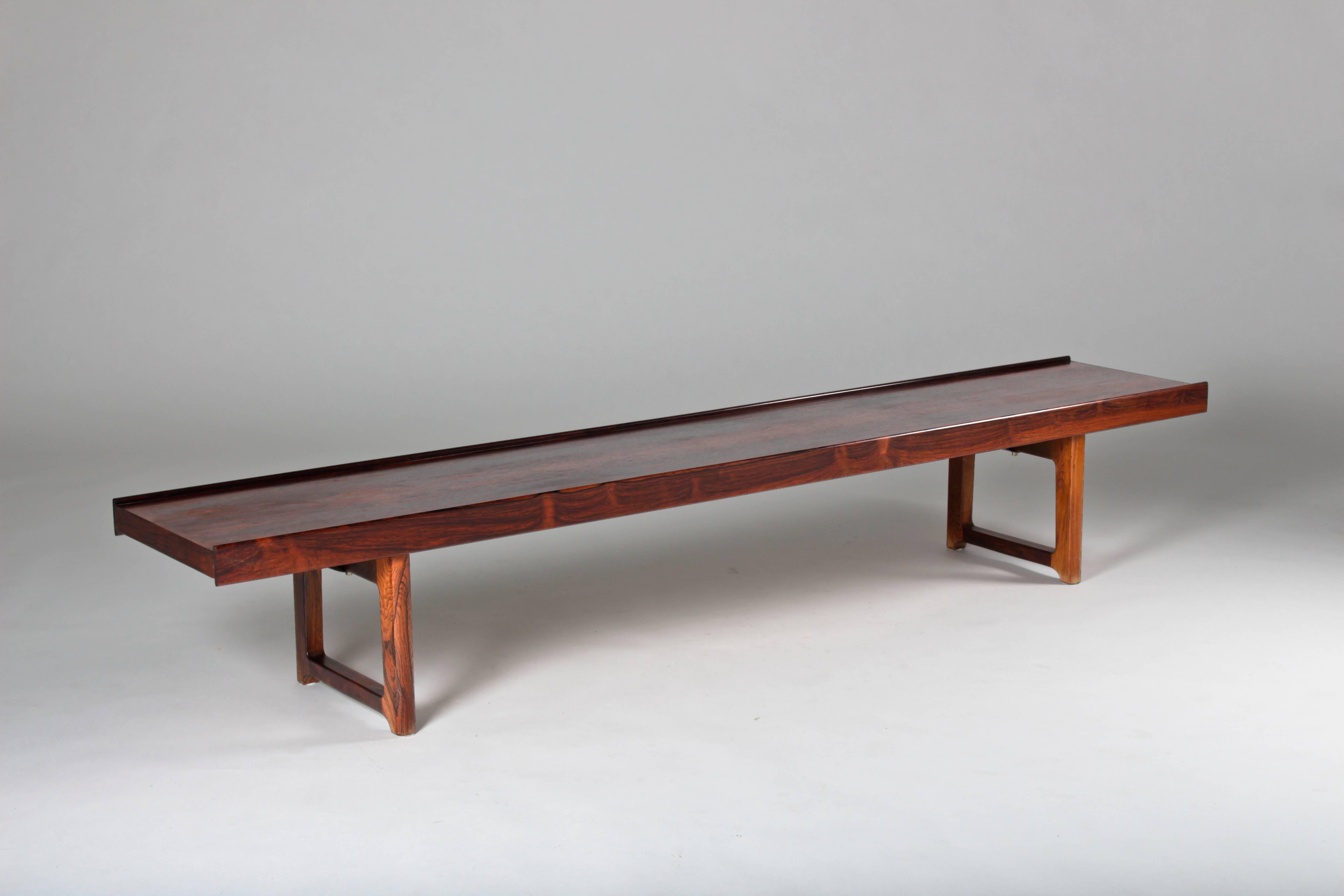 Krobo bench by Torbjørn Afdal in dark rosewood. This bench was covered in a blanket that was attached to the underside by the previous owner. Therefor the surface is in original near mint condition, not even bleached by the sun.
The underside shows