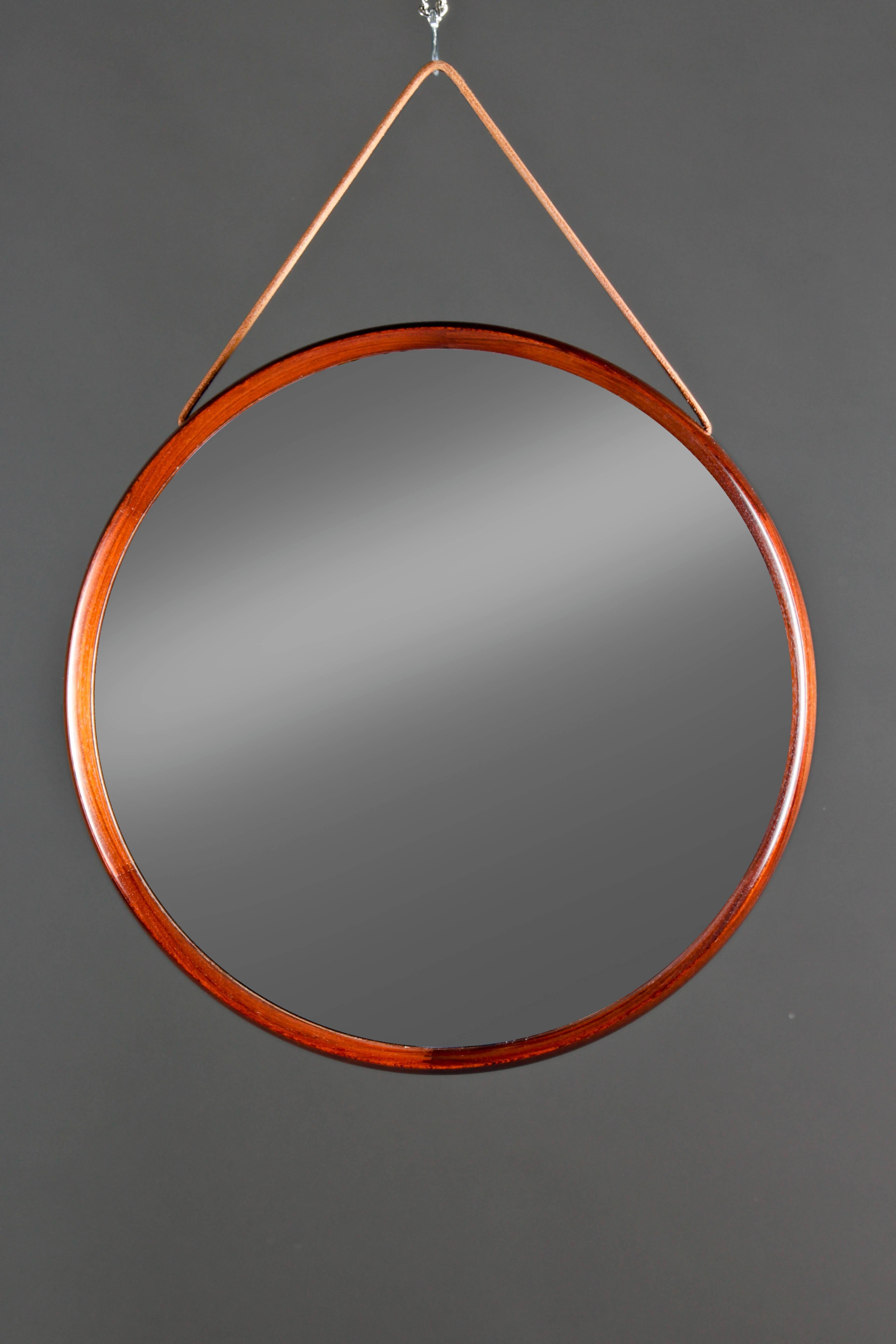 Swedish mirror by Uno & Östen Kristiansson for Luxus in rosewood with leather strap. The mirror is in excellent condition with superb craftsmanship.