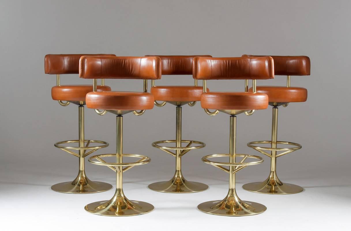 A set of five barstools in brown leather and brass colored metal by Johanson Design in Markaryd, Sweden, from the Scandinavian Mid-Century Modern design era. These barstools were made for public use and show great quality. The chairs are in a very