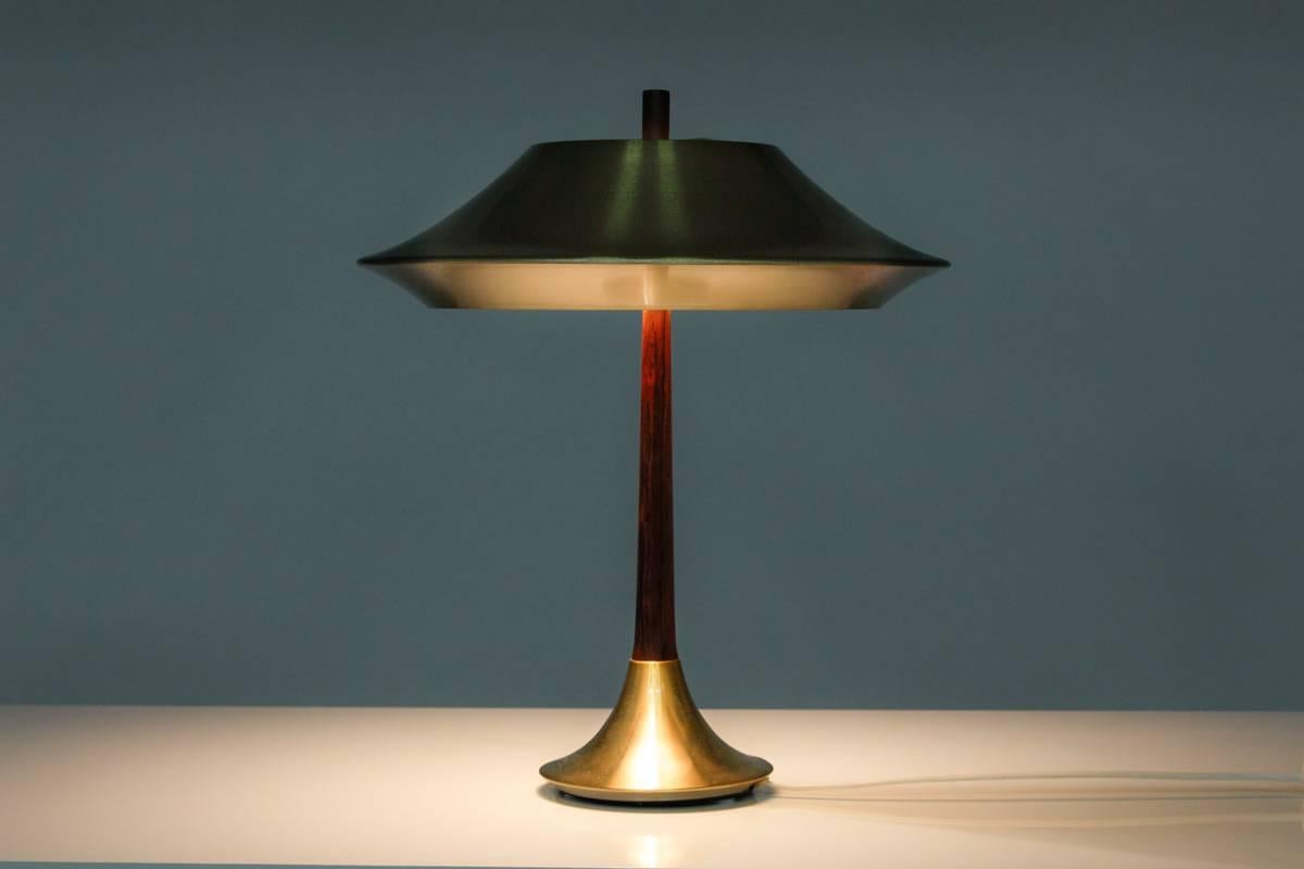 Table lamp in yellow metal and rosewood by Fog & Mørup, Denmark
The elegant curves combined with the beautiful contrasts between the metal and rosewood gives this lamp an exclusive touch. 
The lamp has been rewired and is in a good vintage