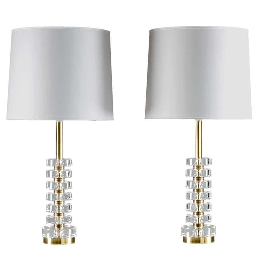 A pair of magnificent table lamps by Carl Fagerlund for Orrefors, Sweden.
The lamps consist of six discs made of clear crystal glass, separated by solid brass discs. 
Condition: The lamps are in excellent original condition. The brass tube on top