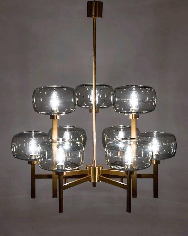Five large chandeliers by Holger Johansson for Westal, Sweden.
These beautiful chandeliers consist of nine rectangular t-shaped brass poles, each holding a grey-blue glass sphere. The brass poles have two different heights that divide the light over