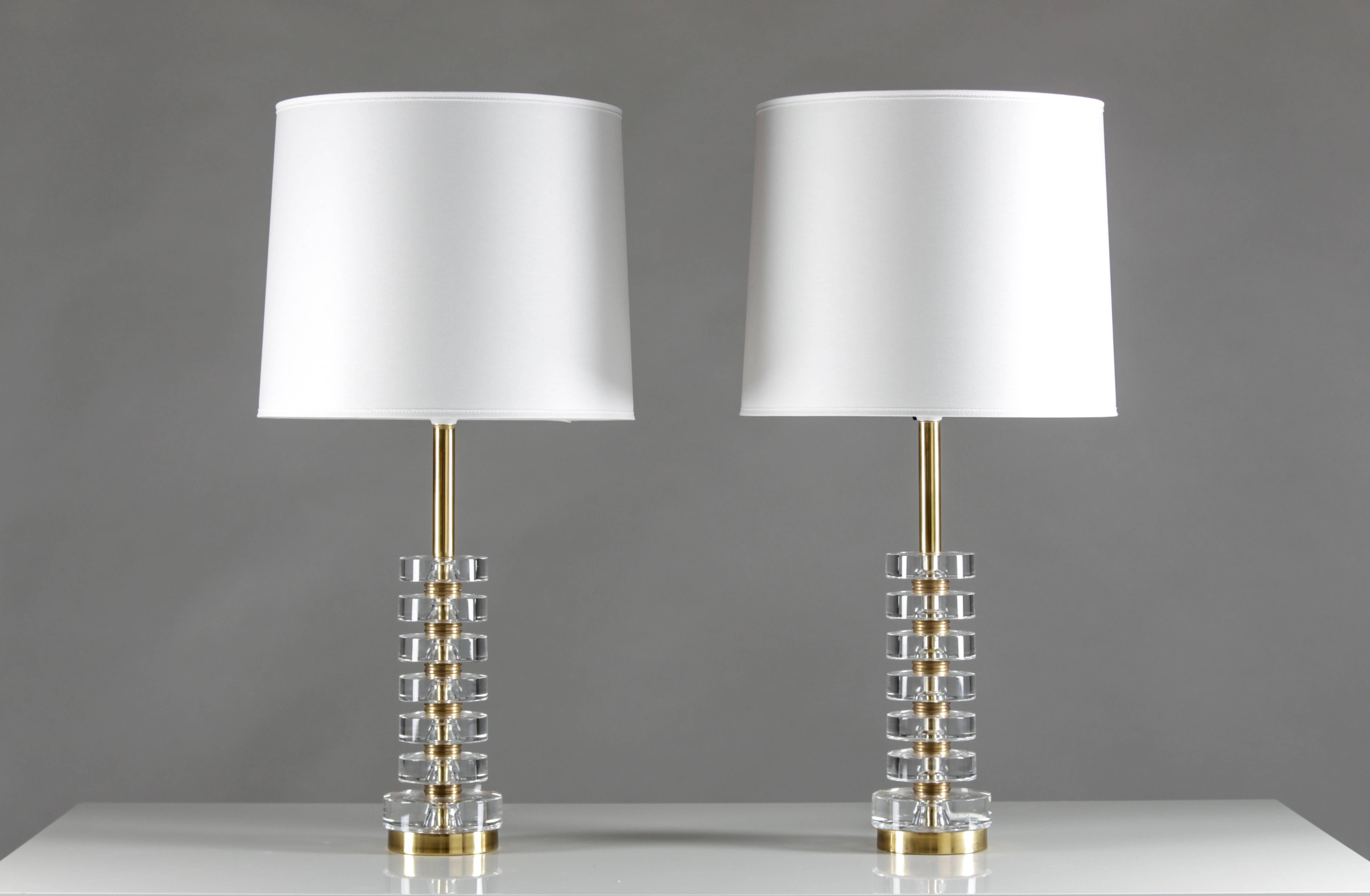 Four magnificent table lamps by Carl Fagerlund for Orrefors, Sweden.
The lamps consist of six discs made of clear crystal glass, separated by solid brass discs. 
Condition: The lamps are in very good original condition. The brass tube on top has