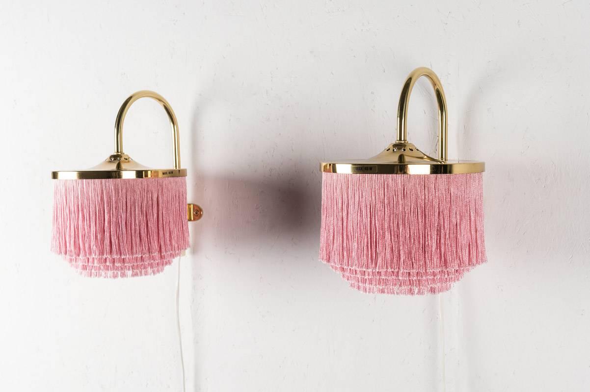 A pair of wall lamps model v140 by Hans-Agne Jakobsson for Markaryd with pink silk fringes.
Condition: The brass parts are in very good condition with only light scratches and dots.
The fringes are in excellent condition.
 