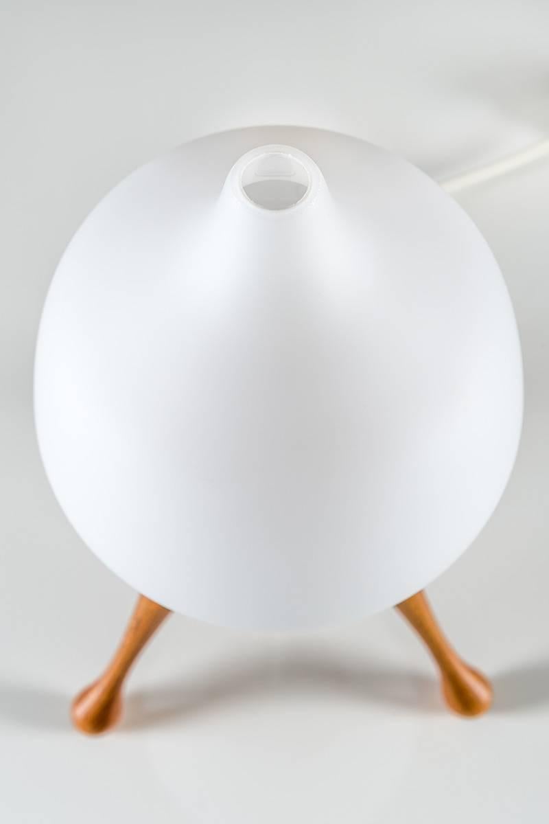 An early table lamp by Uno & Östen Kristiansson for Luxus. This lamp features a tripod base in oak with an opaline glass shade on top. Very minimalistic and great craftsmanship which is significant for Luxus' earlier productions.
  