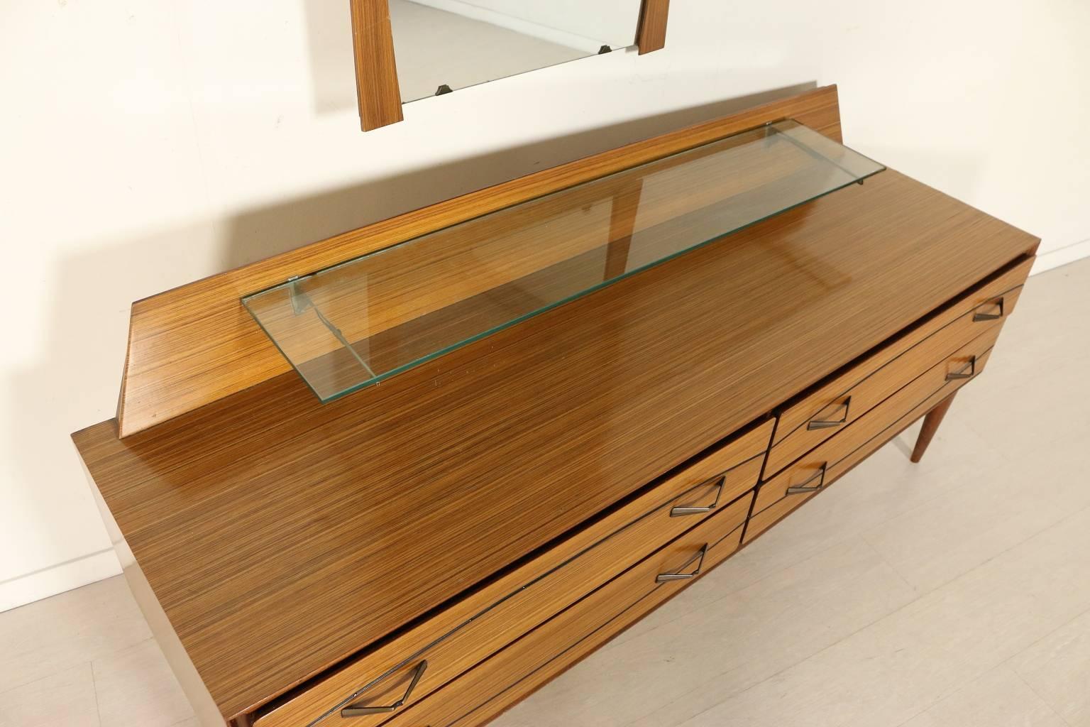 A chest of drawers with mirror, rosewood veneer, glass top. Manufactured in Italy, 1960s. Dimensions of the mirror: H 99 cm, L 64 cm, W 3 cm.