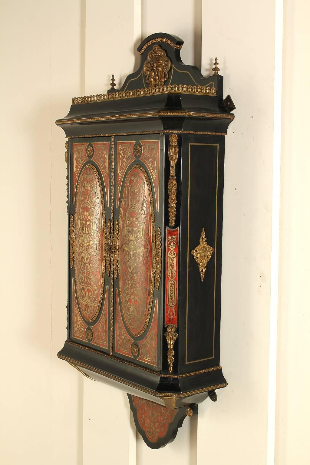 Napoleon III hanging cabinet, Boulle style, with basement and apron. Two doors with curved panels. Railings on the top and crest with mask. Turtle inserts with brass inlays, friezes and gilded brass frames. Manufactured in France, late 19th century.