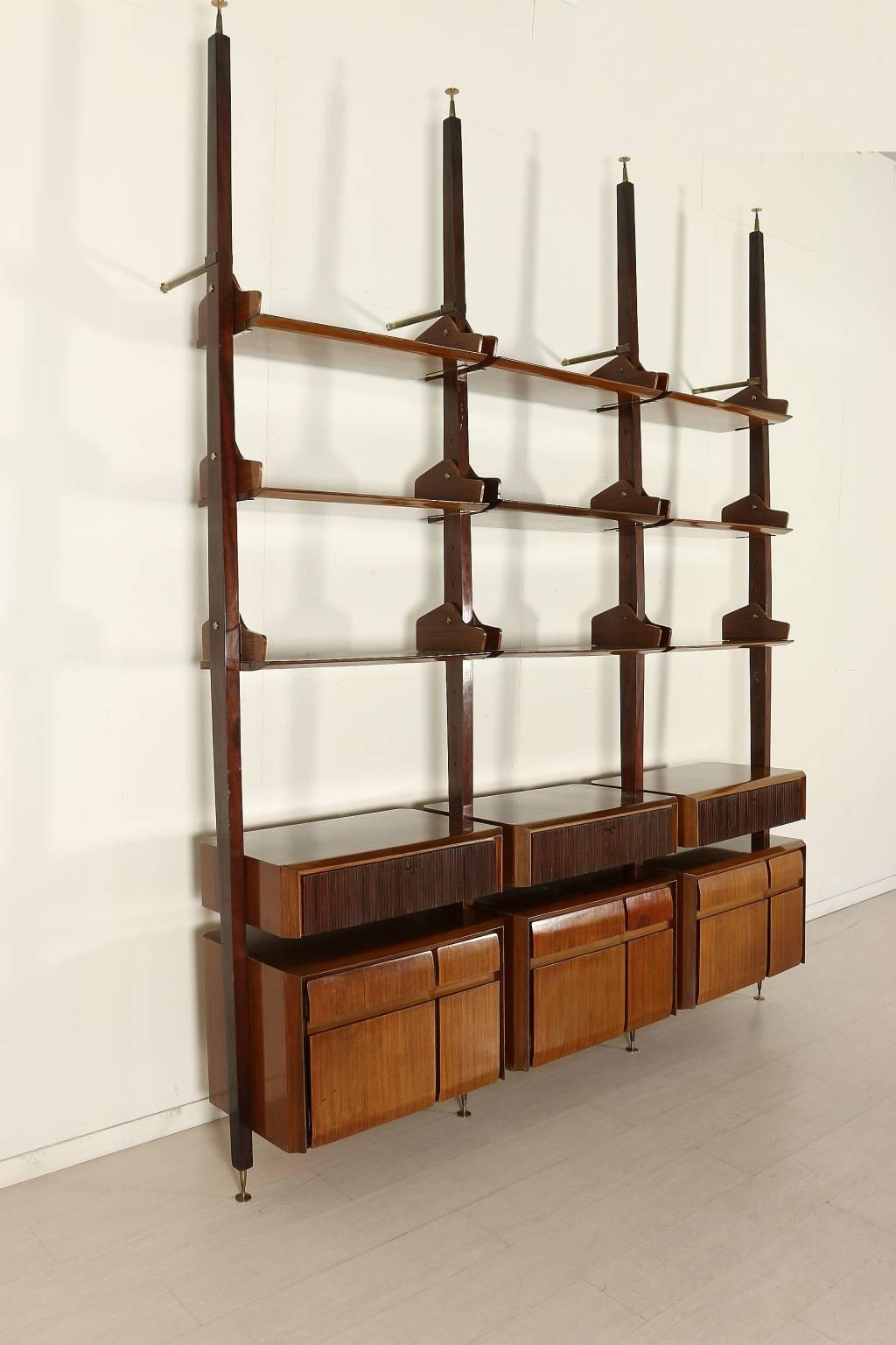 A floor-to-ceiling bookcase, teak veneer, mahogany uprights, decorated drawers, brass. Manufactured in Italy, 1950s-1960s.