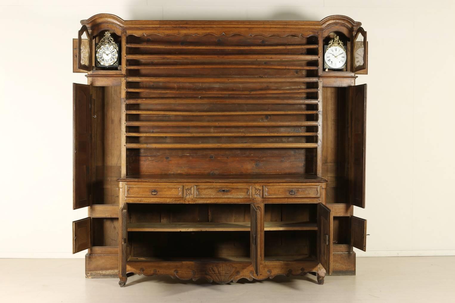 Late 18th century walnut cupboard with plate rack and (not coeval) clocks, three doors and three drawers. Front with typical Provence carvings. Manufactured in France.