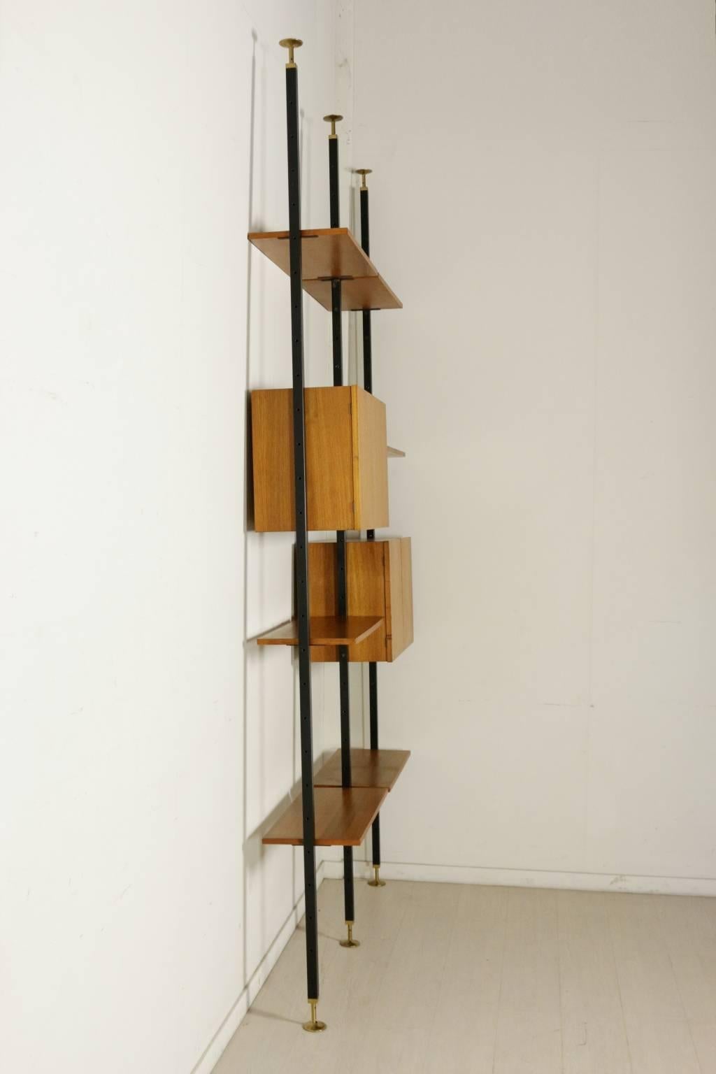 A floor-to-ceiling bookcase with elements adjustable in height, teak veneer, metal uprights with brass tips. Manufactured in Italy, 1950s-1960s.