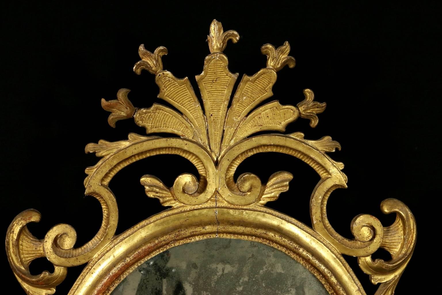 Early 18th century Baroque linden carved and gilded wall mirror for fireplace. Manufactured in Torino (Italy). One central mirror with two lateral pillars with mirrors, French taste capitals and carved crest with curls, also reproduced in the