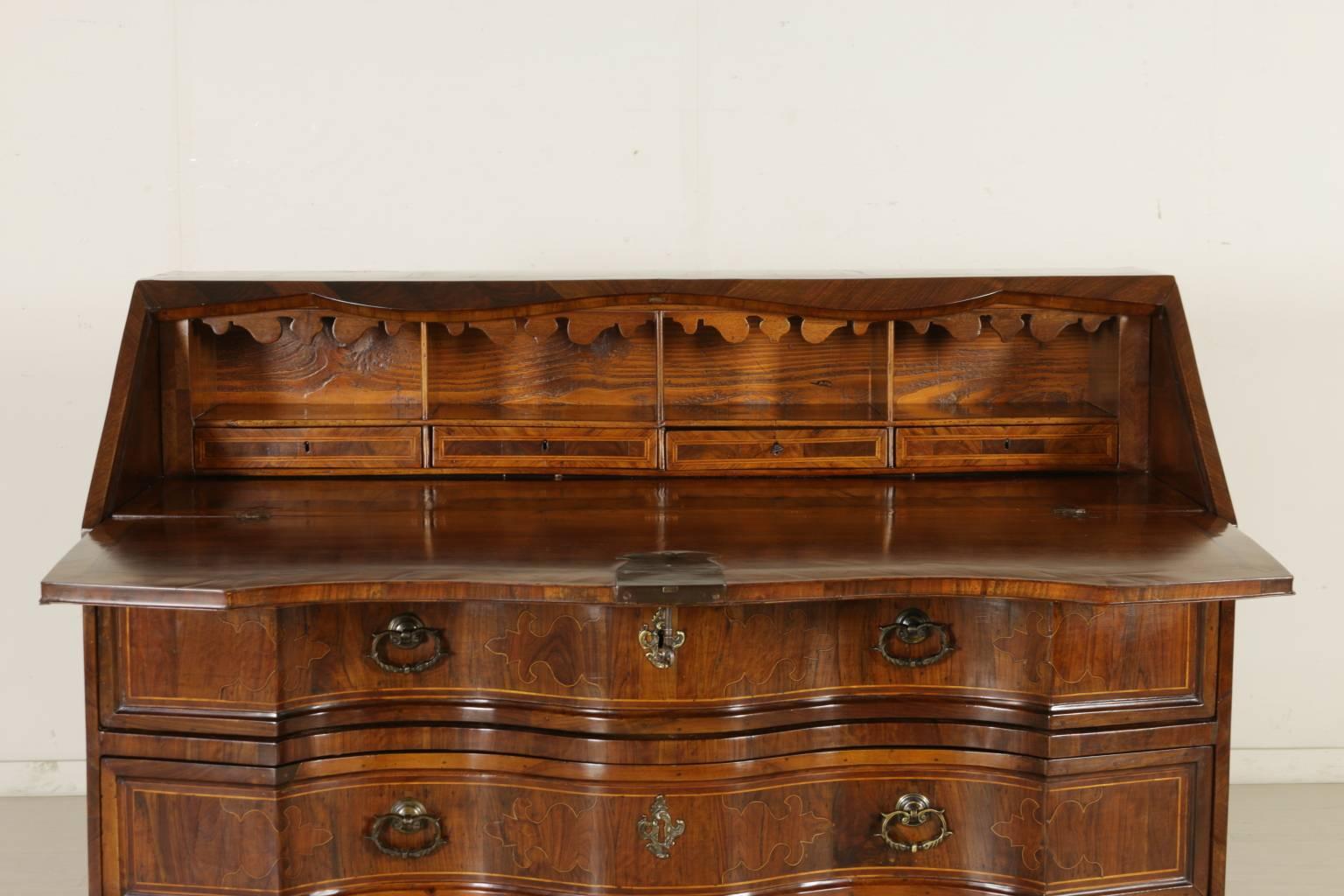 An early 18th century walnut and olive tree veneered drop-leaf desk and chest of drawers, manufactured in Northern Italy. Shaped drop-leaf door and three drawers. Four internal drawers with locks and open compartments. Olive tree and maple inserts.