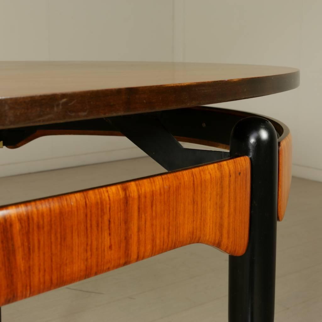 An elliptical table, teak veneered top, rosewood band, metal legs, brass. Manufactured in Italy, 1950s-1960s.