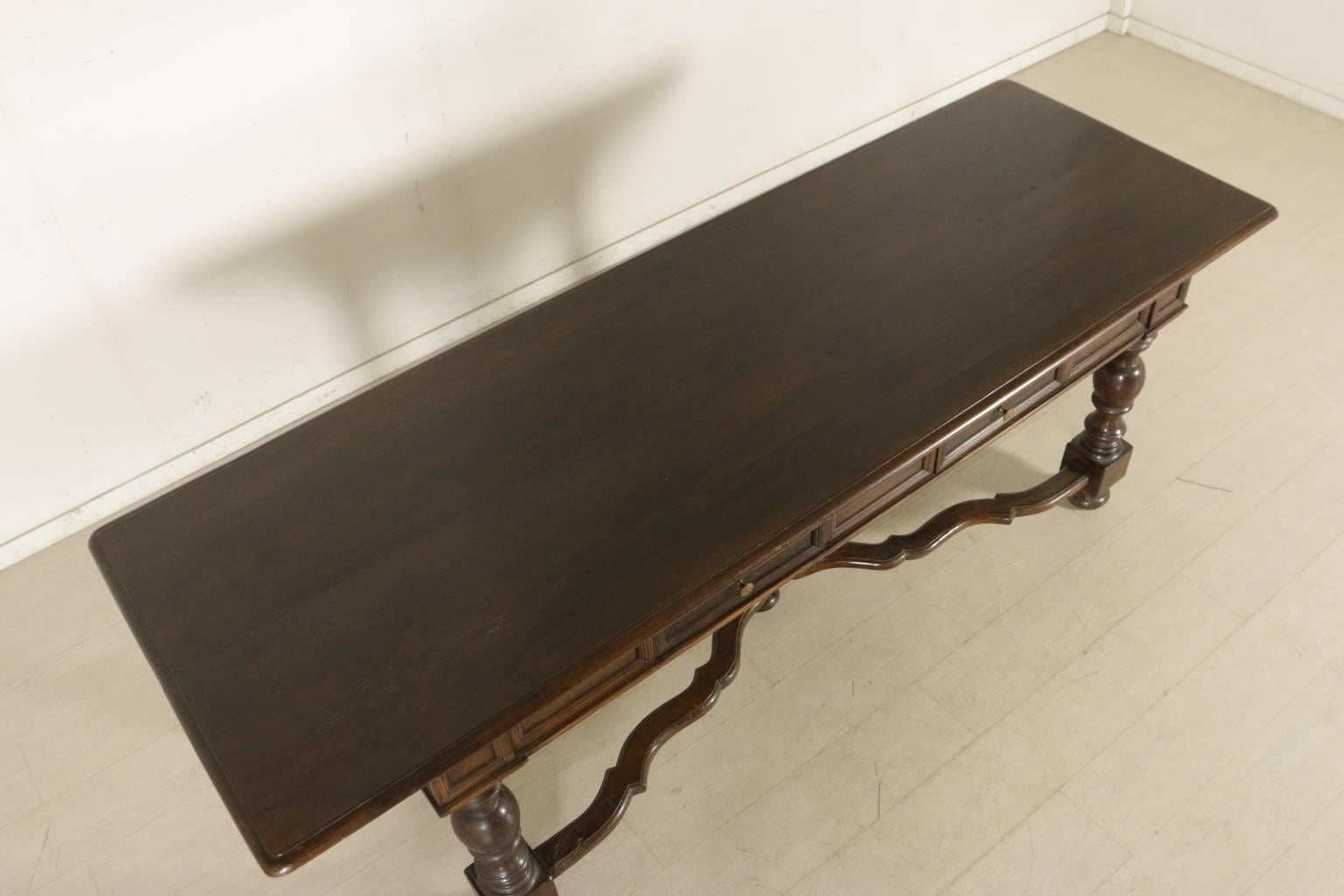 A large walnut table with turned legs jointed by shaped and turned cross stretchers. A pair of drawers on the band. Solid walnut top. Manufactured in Italy, first half of the 20th century.